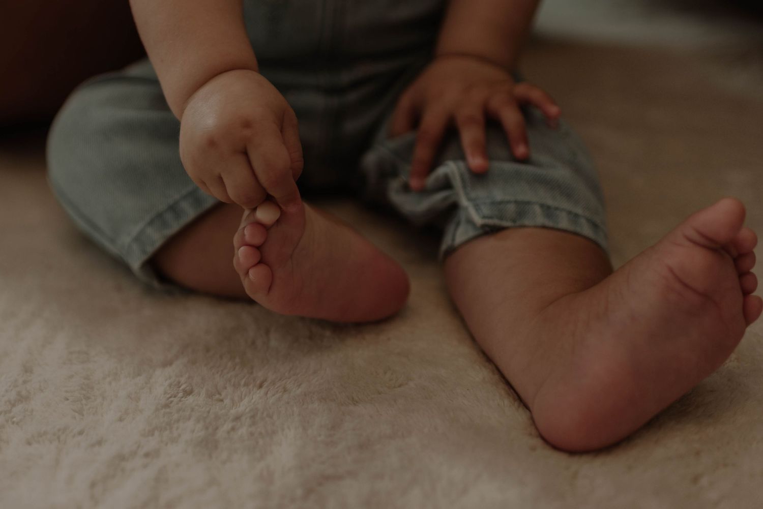 Baby's tiny feet resting on soft beige carpet showing different developmental stages of movement and positioning.