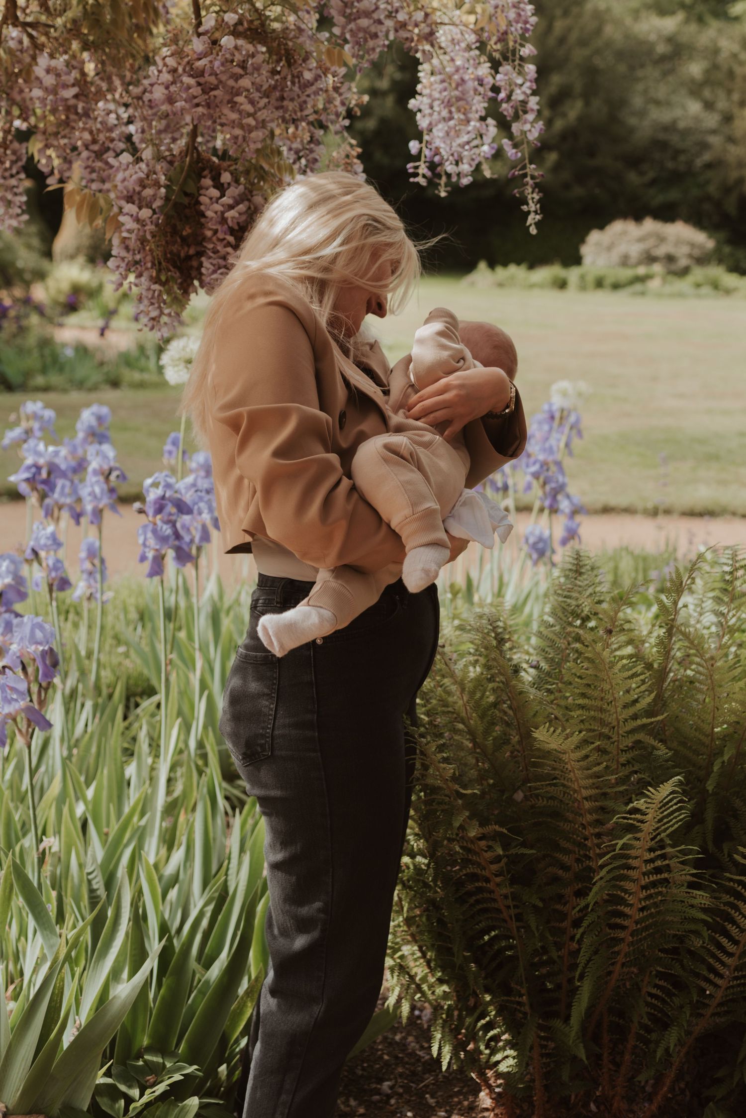 Spring garden scene with flowering wisteria and iris flowers as backdrop for tender family moment.