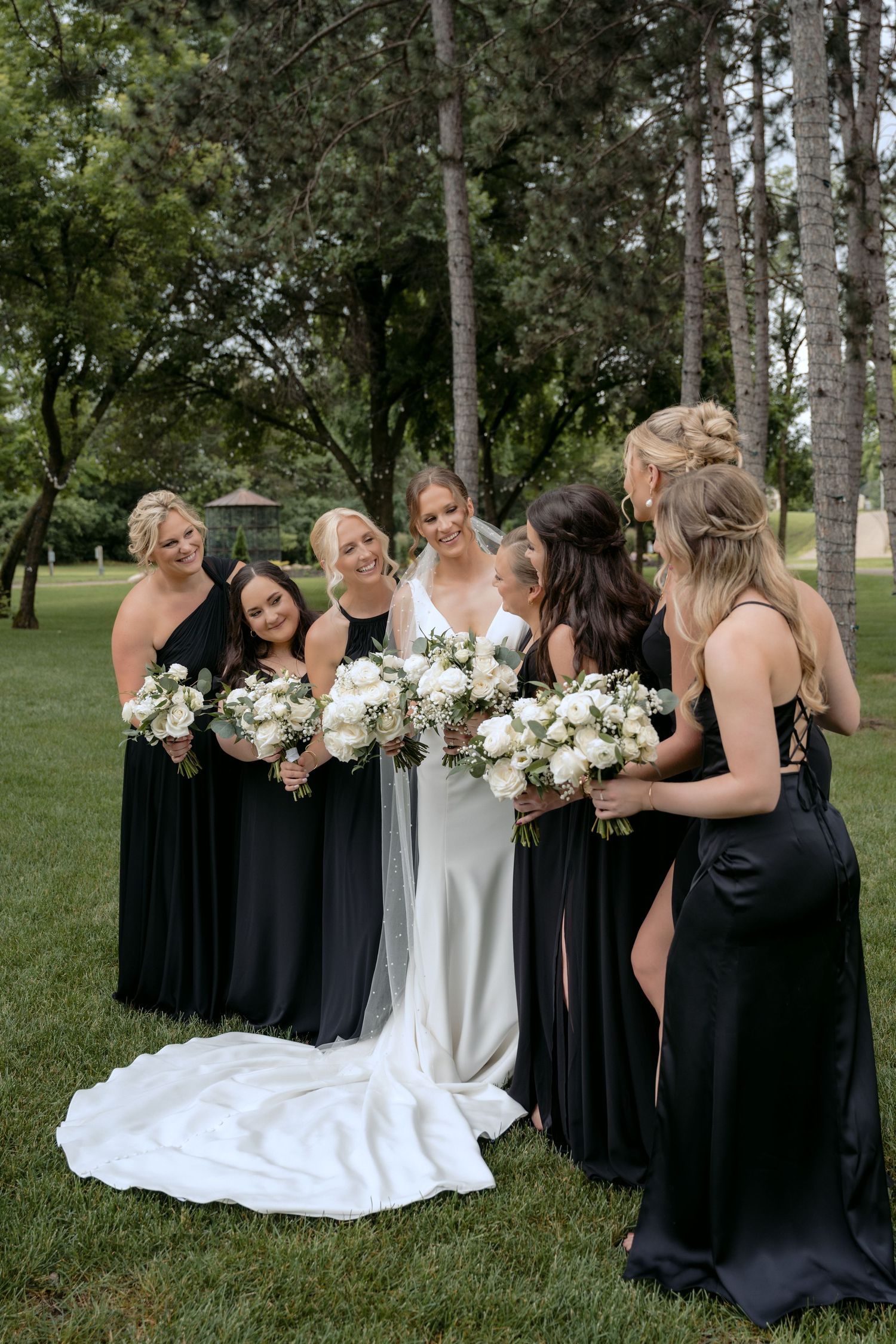 bridal party holding bouquets looking at each other with smiles at la pointe events in somerset wisconsin