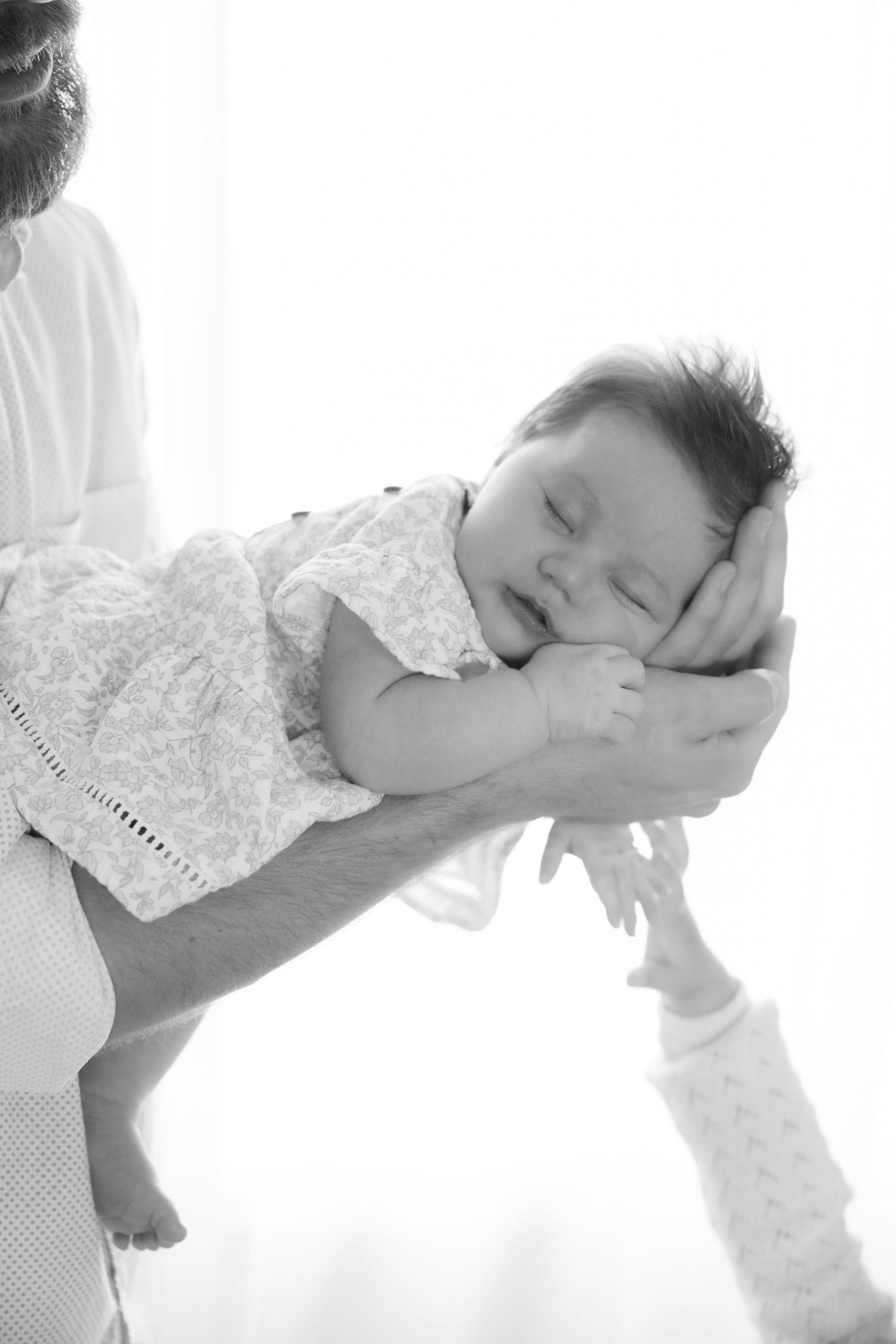 Dad holds newborn baby on outstretched arms during in home lifestyle newborn session in Somerset, WI.