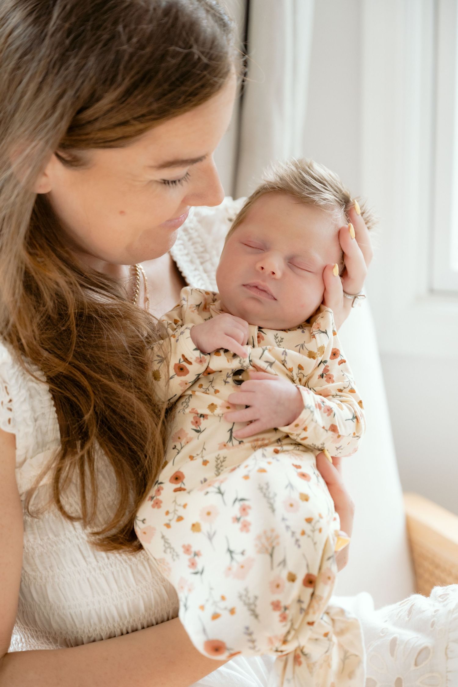 Mother looks adoringly at her sleeping newborn baby during a lifestyle in home newborn session in the Twin Cities, MN.