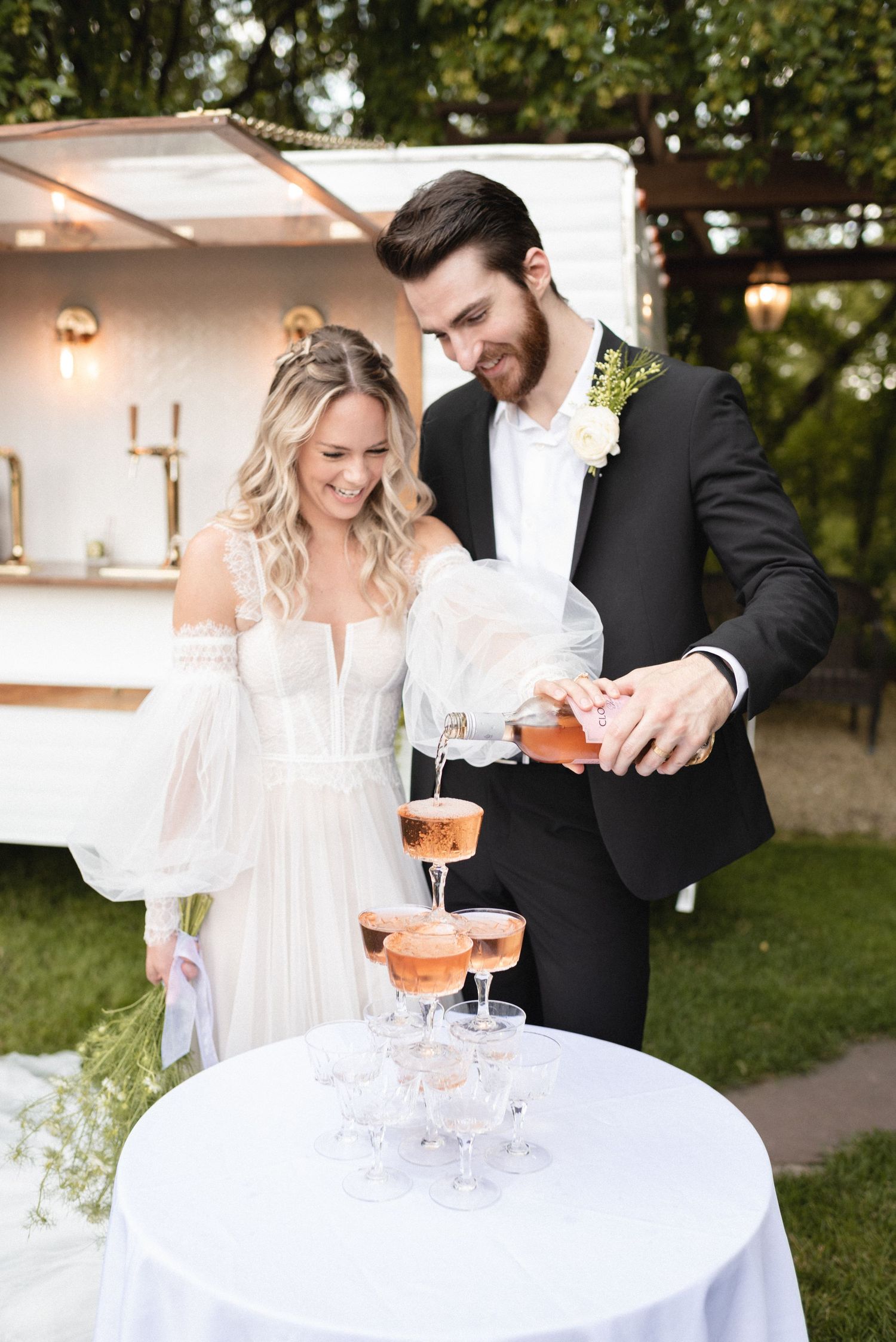 bride and groom filling a champagne fountain during their wedding day at trellis weddings featuring piccadilly mobile bar in stillwater mn