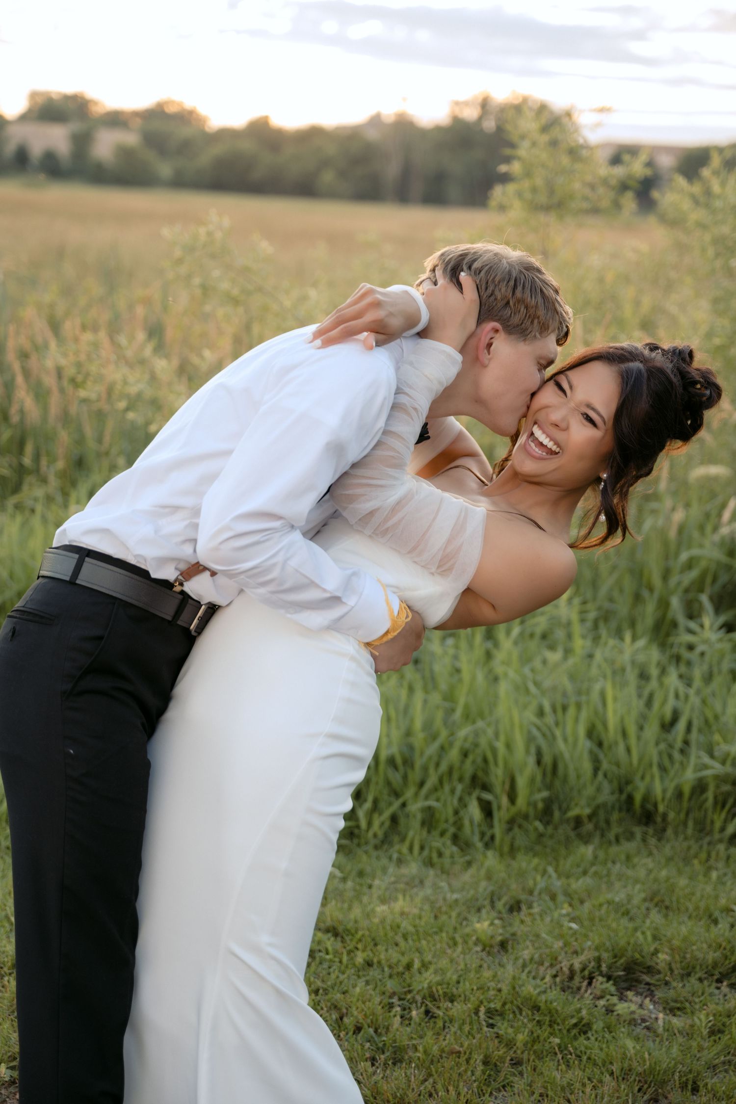 bride and groom kissing and laughing during sunset portraits in wisconsin