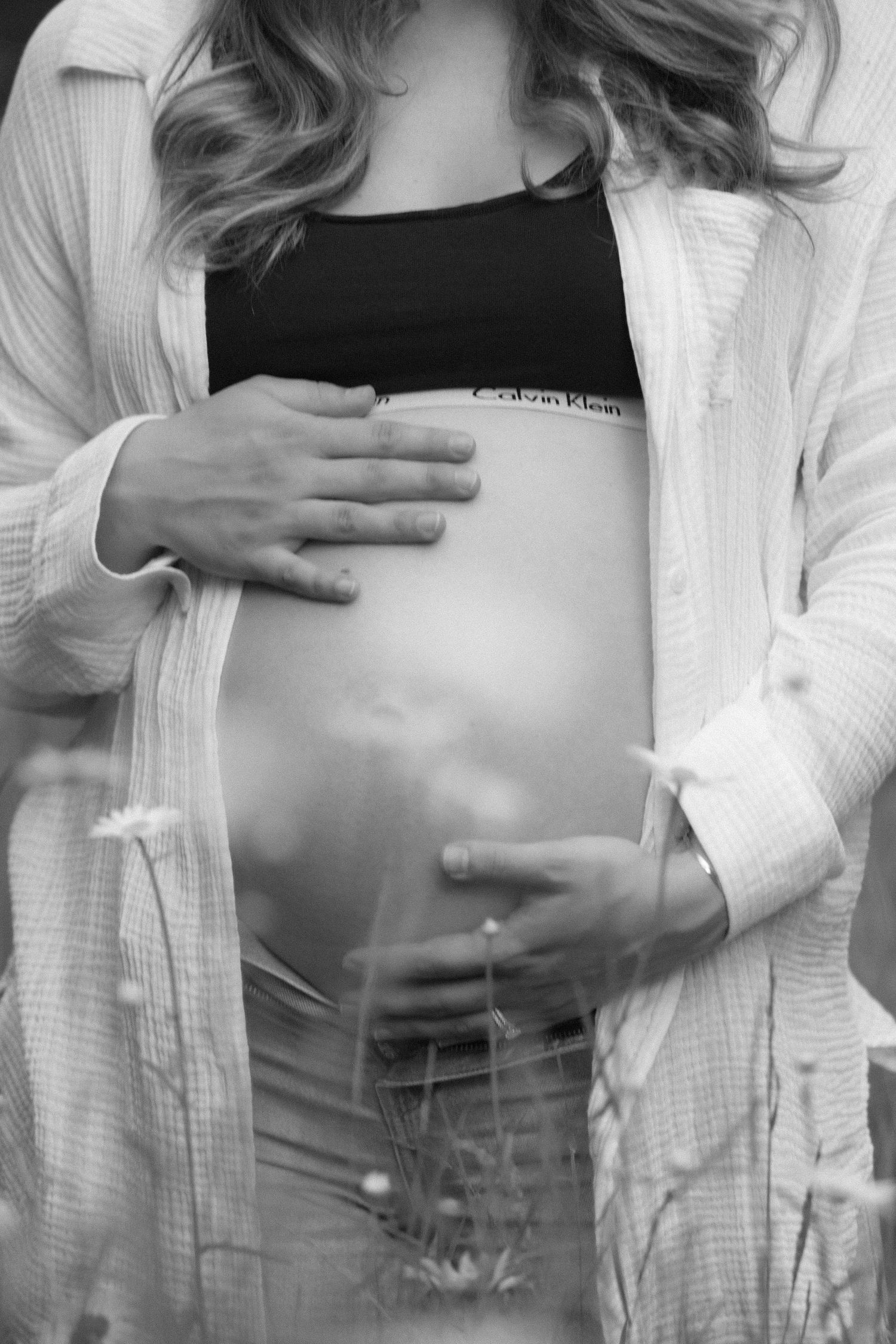 closeup of baby bump personal portraits of jagger rose photography during outdoor maternity session in a flower field wearing calvin klein