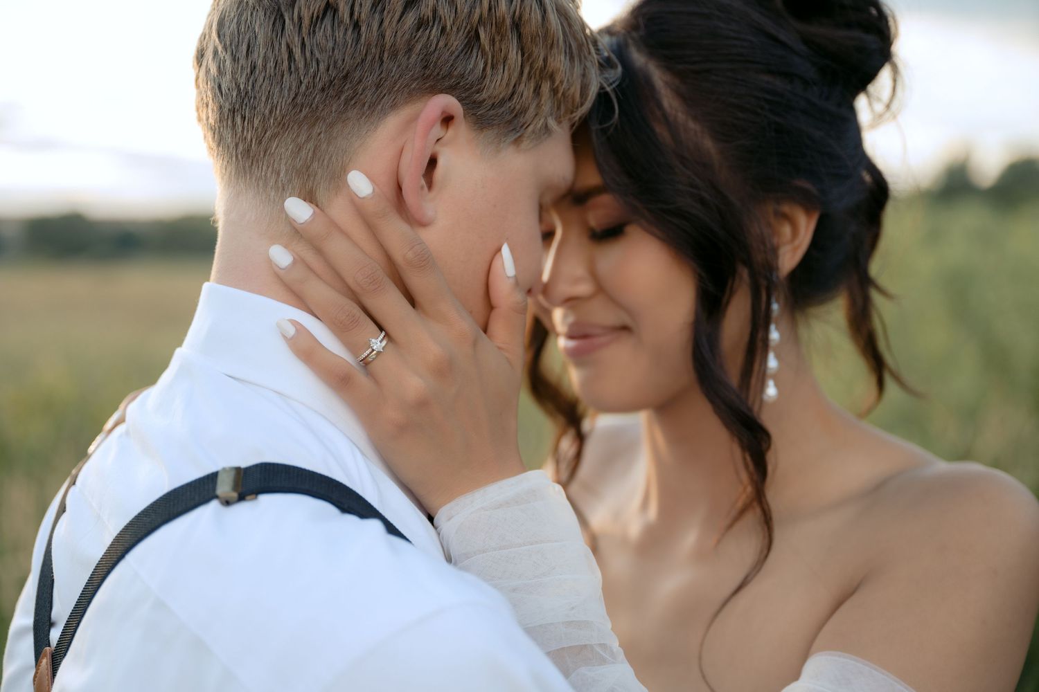 Closeup of bride & groom, bride's hand caresses grooms face with a focus on her wedding bands at Millennium Gardens in Plymouth, Minnesota.