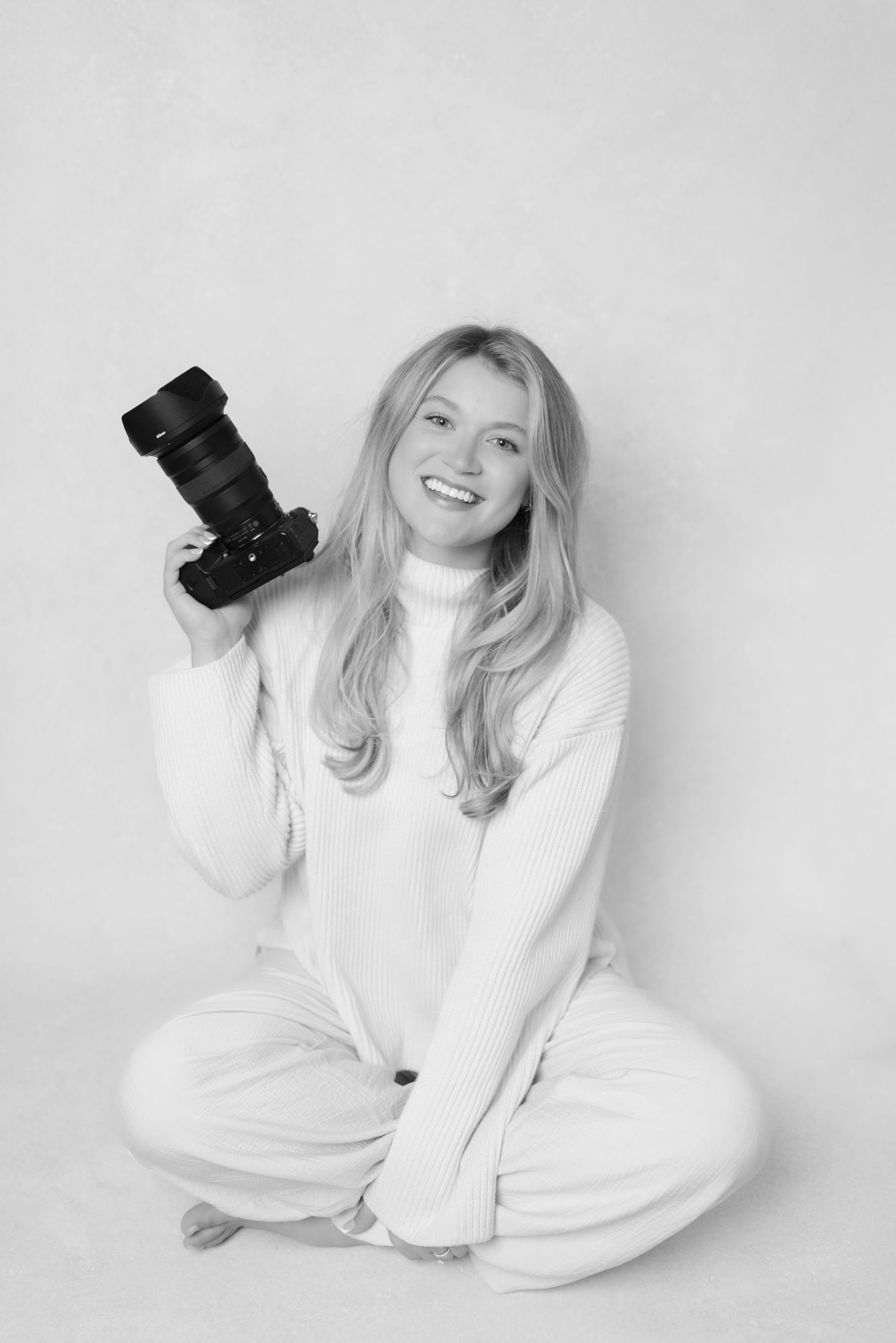 headshot of wedding photographer, Jagger, in her in-home studio holding her camera.