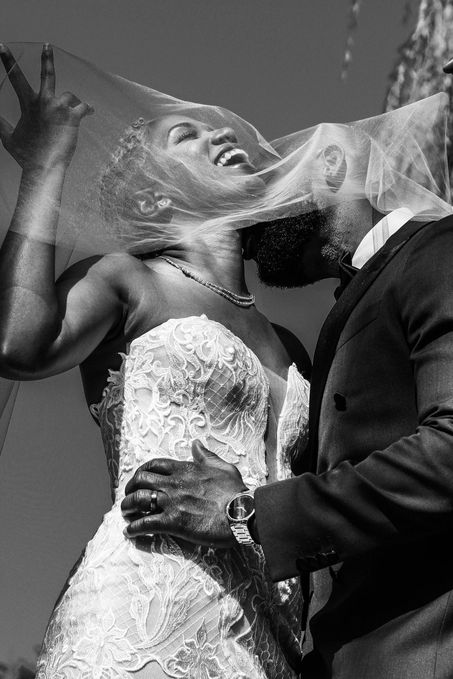 Black and white wedding photo capturing joyful laughter and movement.