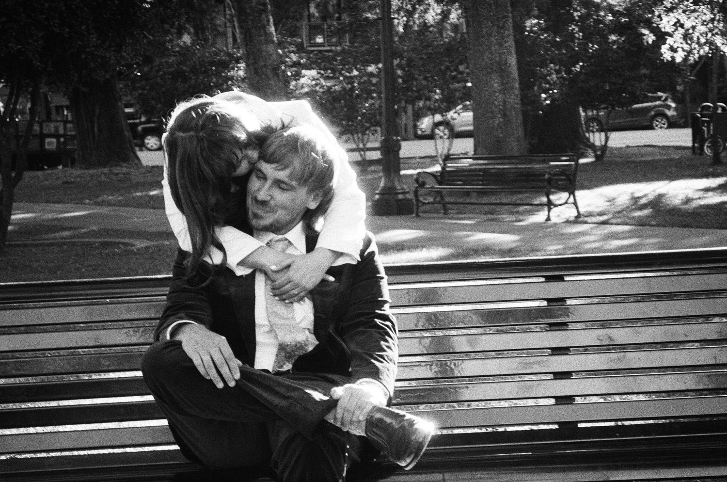 Couple sitting together on a wooden bench in a park setting. Photographed on film in the North Bay