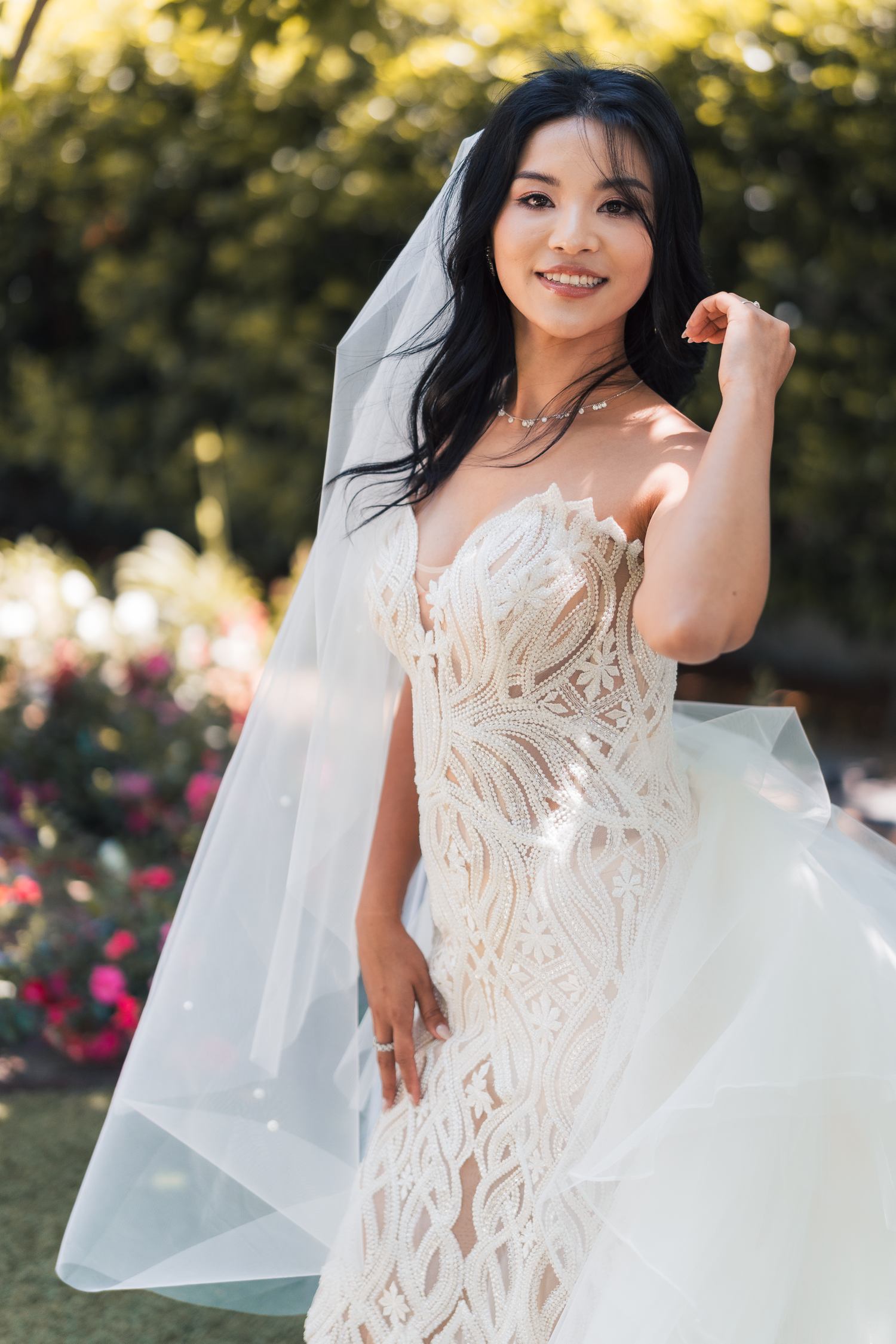 Elegant bride in a detailed white lace gown with flowing veil in a garden setting at Carneros Resort and Spa in Sonoma County.