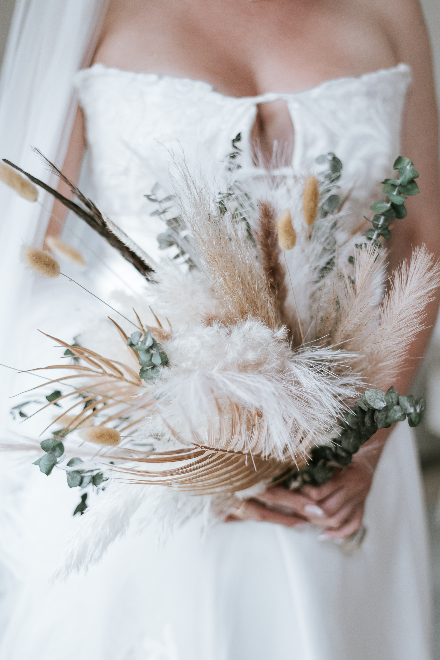 Elegant bridal bouquet featuring delicate white pampas grass, feathers and eucalyptus details.