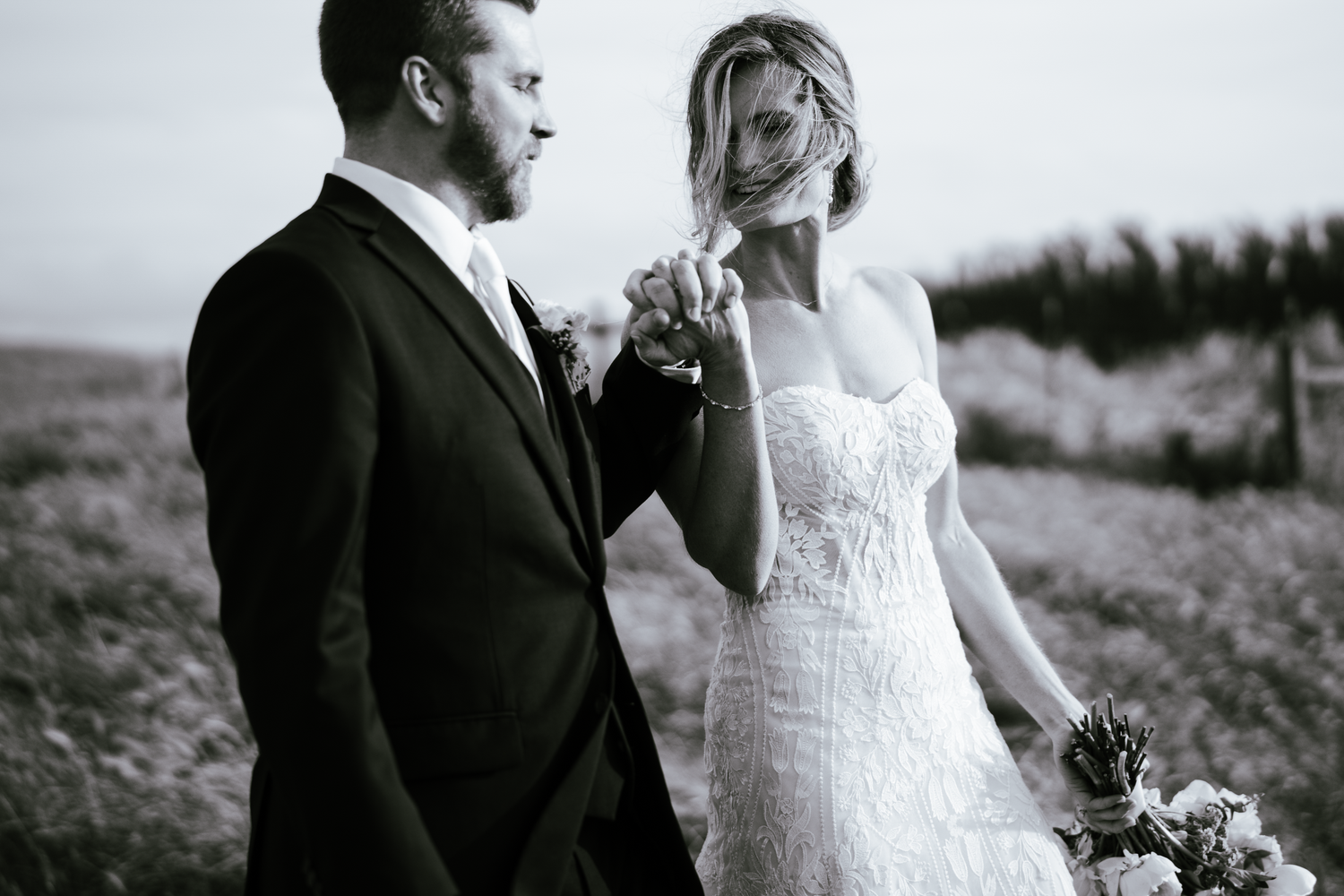 A black and white wedding photo of a couple in formal attire standing together in an outdoor field at Olympia's Valley Estate in Petaluma.