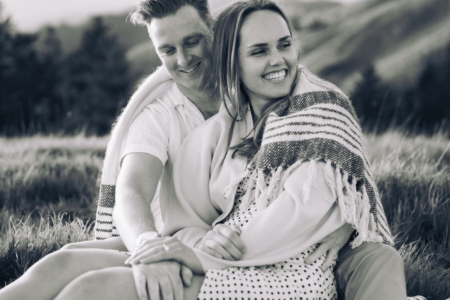 Couple laughs together while sitting in outdoor setting during photo session on Mount Tamalpais in Marin County.