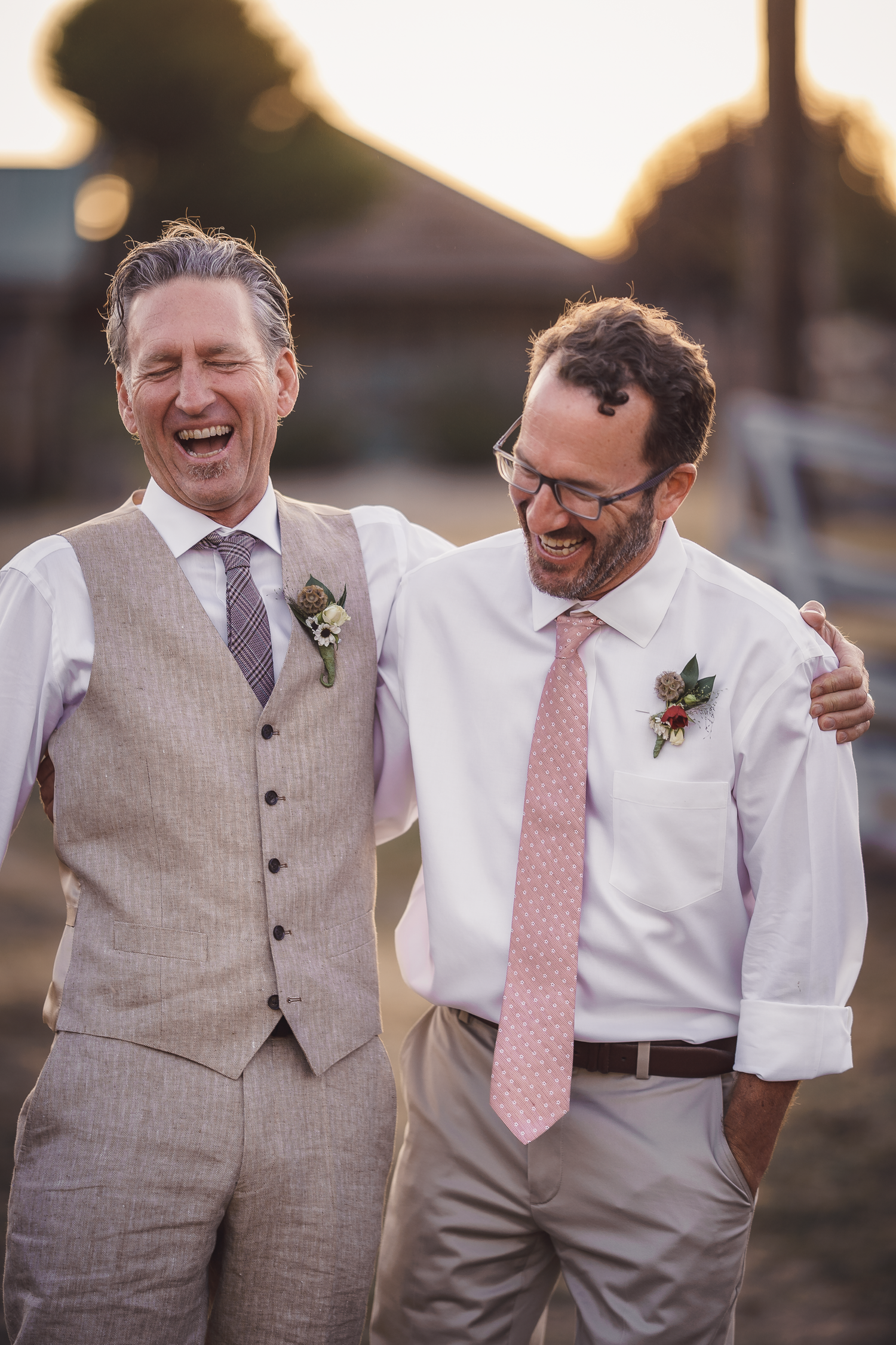 Groom and Groomsmen share laughs during sunset wedding photos wearing light gray vests and pink ties at Cow-Track-Ranch in Marin County.