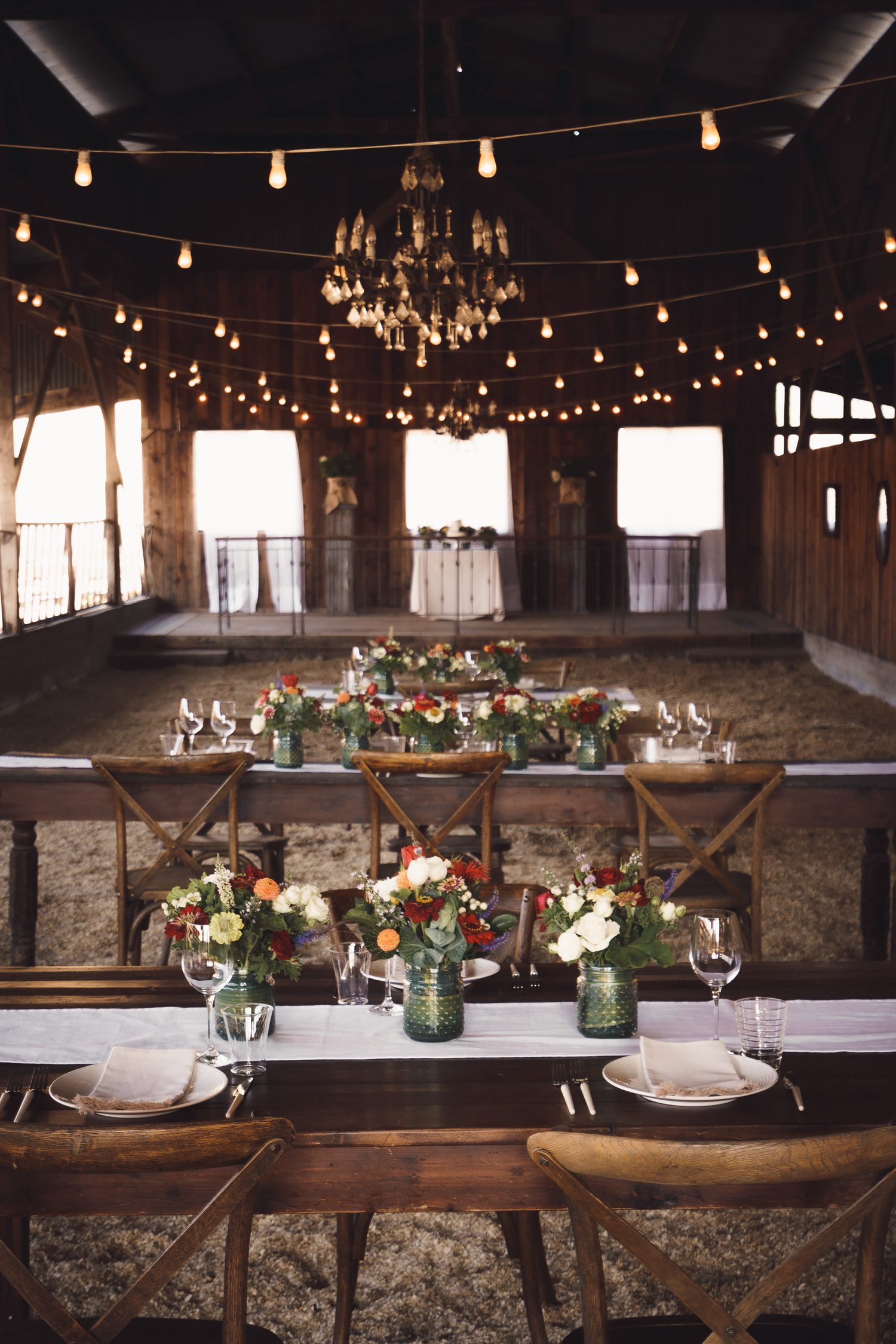 Elegant table settings with string lights and floral centerpieces in mason jars at the rustic wedding venue, Cow-Track-Ranch in Marin.