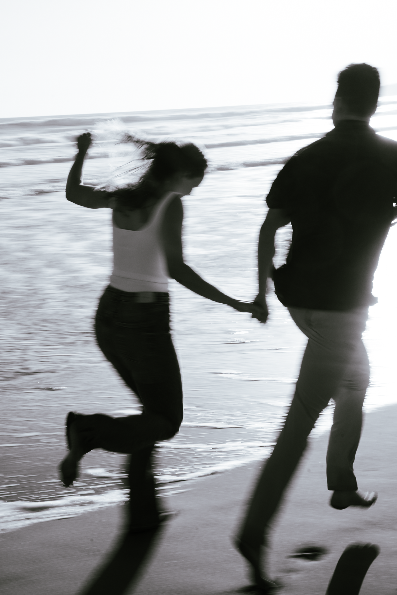Silhouettes of couple dancing and jumping on a beach at sunset during engagement photoshoot at Stinson Beach in Marin County.