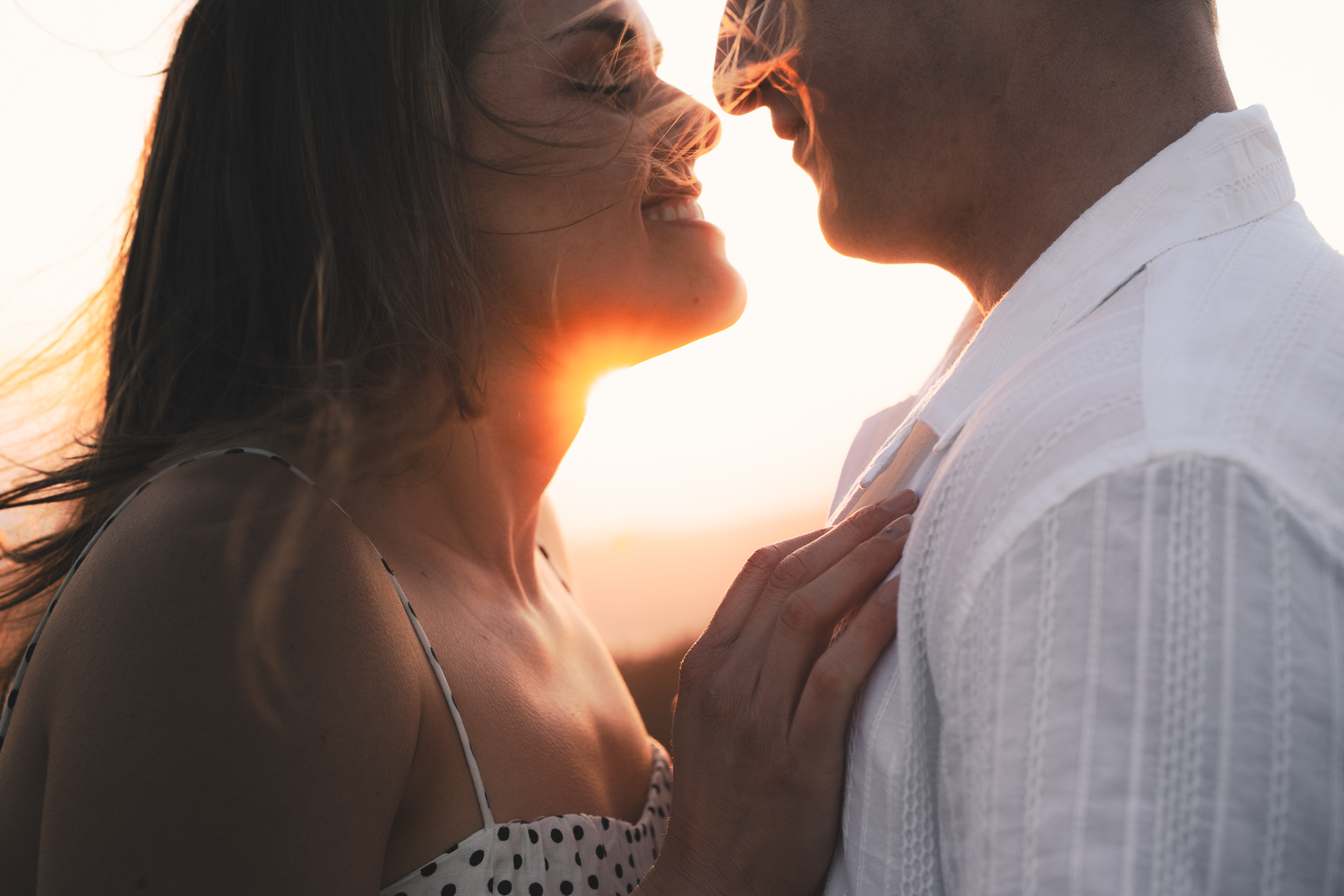 Romantic couple embraces during golden sunset on on Mount Tamalpais in Marin County with warm glowing light.