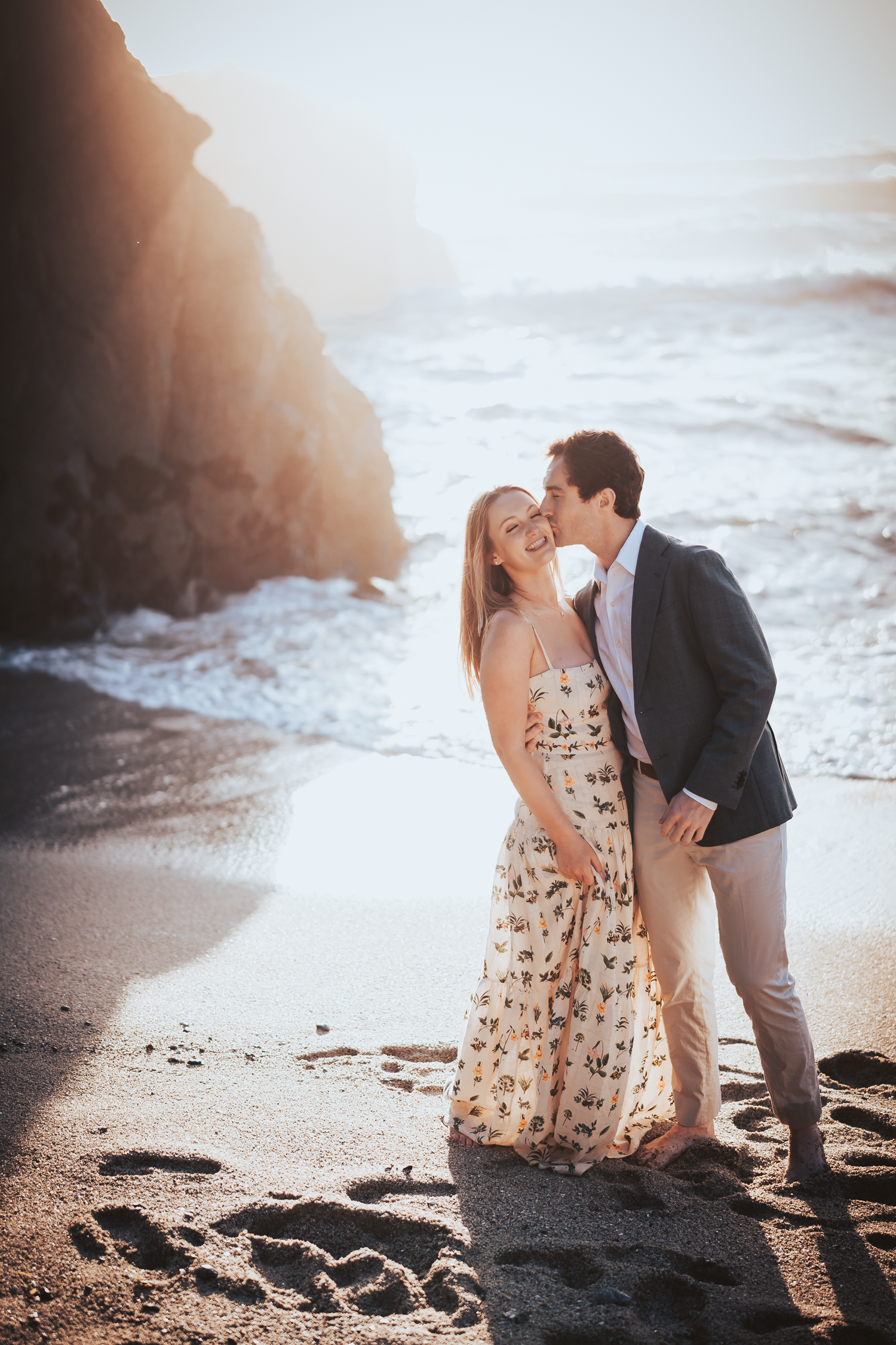 Romantic beach photoshoot at sunset with couple posing near rocky cliffs at Bodega Bay in Sonoma County