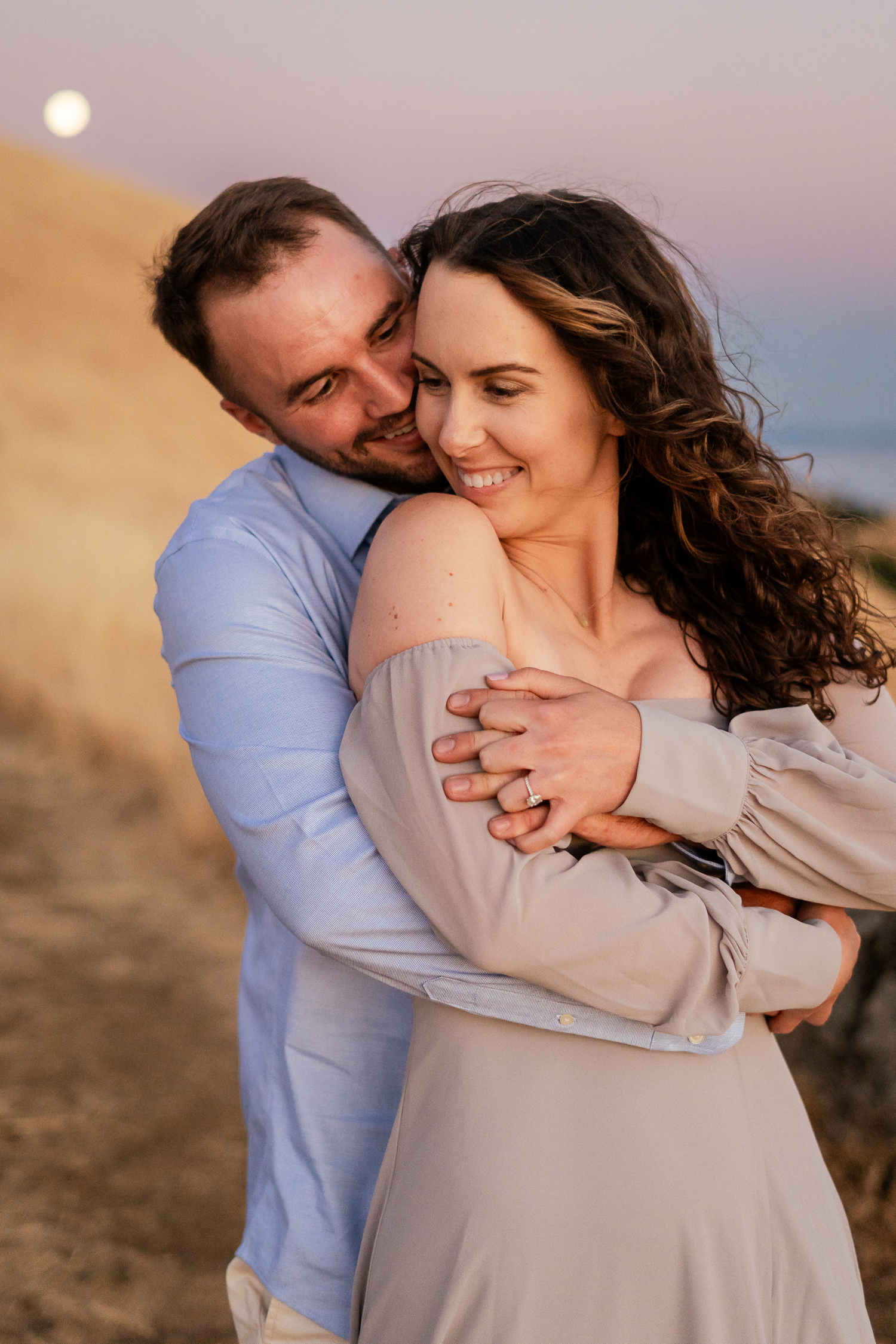 Couple during an engagement photoshoot sharing an intimate moment at sunset with warm golden light on Mount Tamalpais in Marin County.