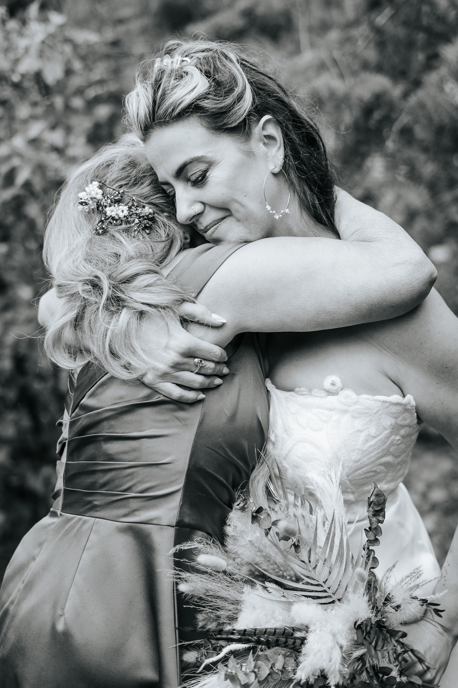 Emotional black and white wedding moment captured between bride and mom in intimate embraces.