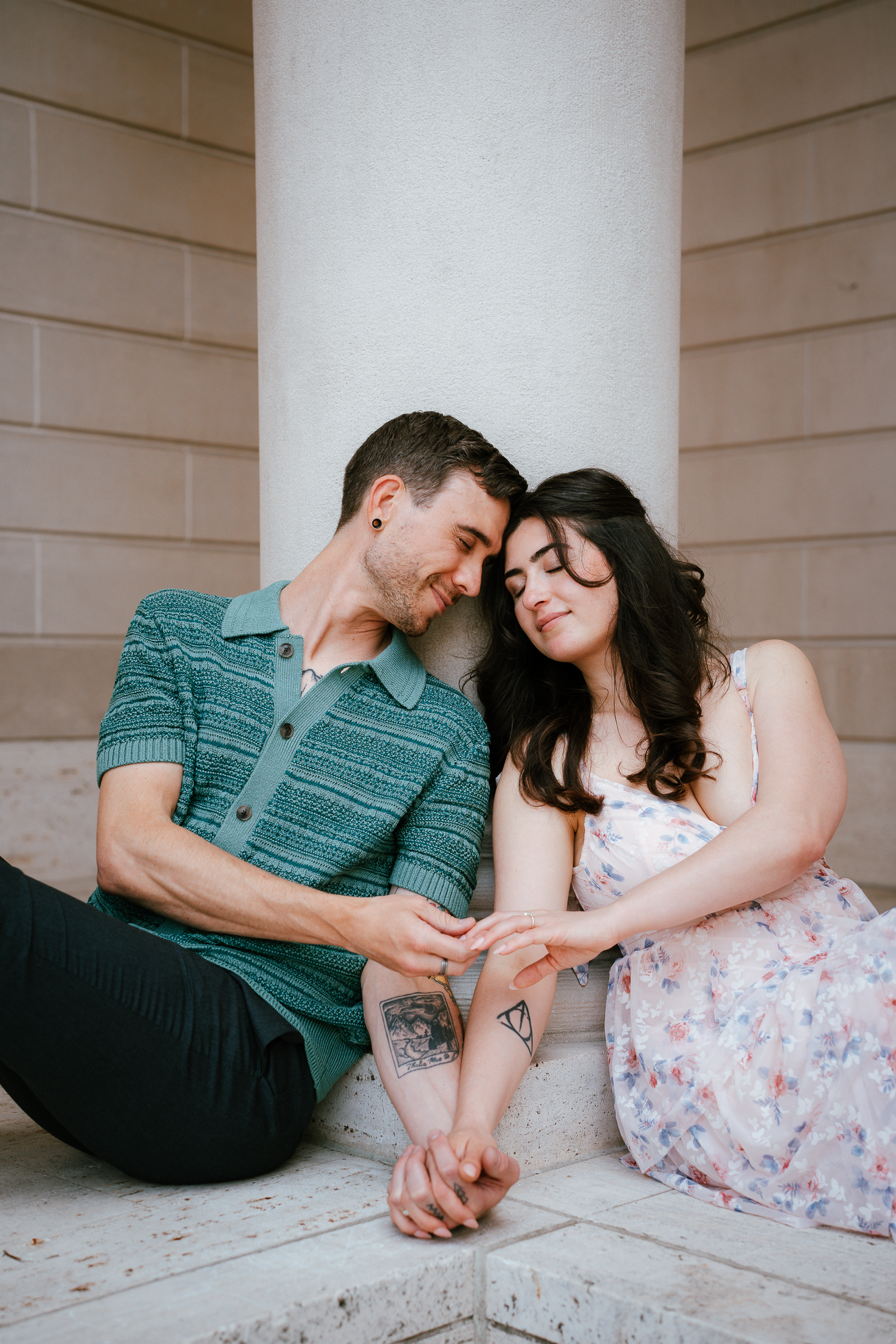 A couple sits intimately together on white steps in a romantic engagement photo series.