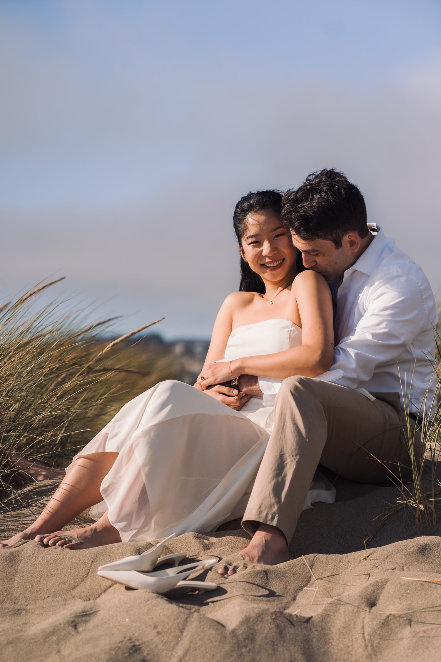 Couple relaxes on sandy beach during intimate seaside photoshoot at Ocean Beach in San Francisco.