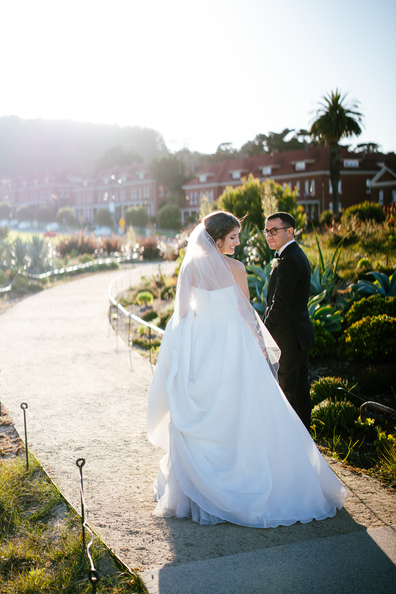 Wedding couple walking along a scenic coastal path during golden hour in the Presidio in San Francisco.