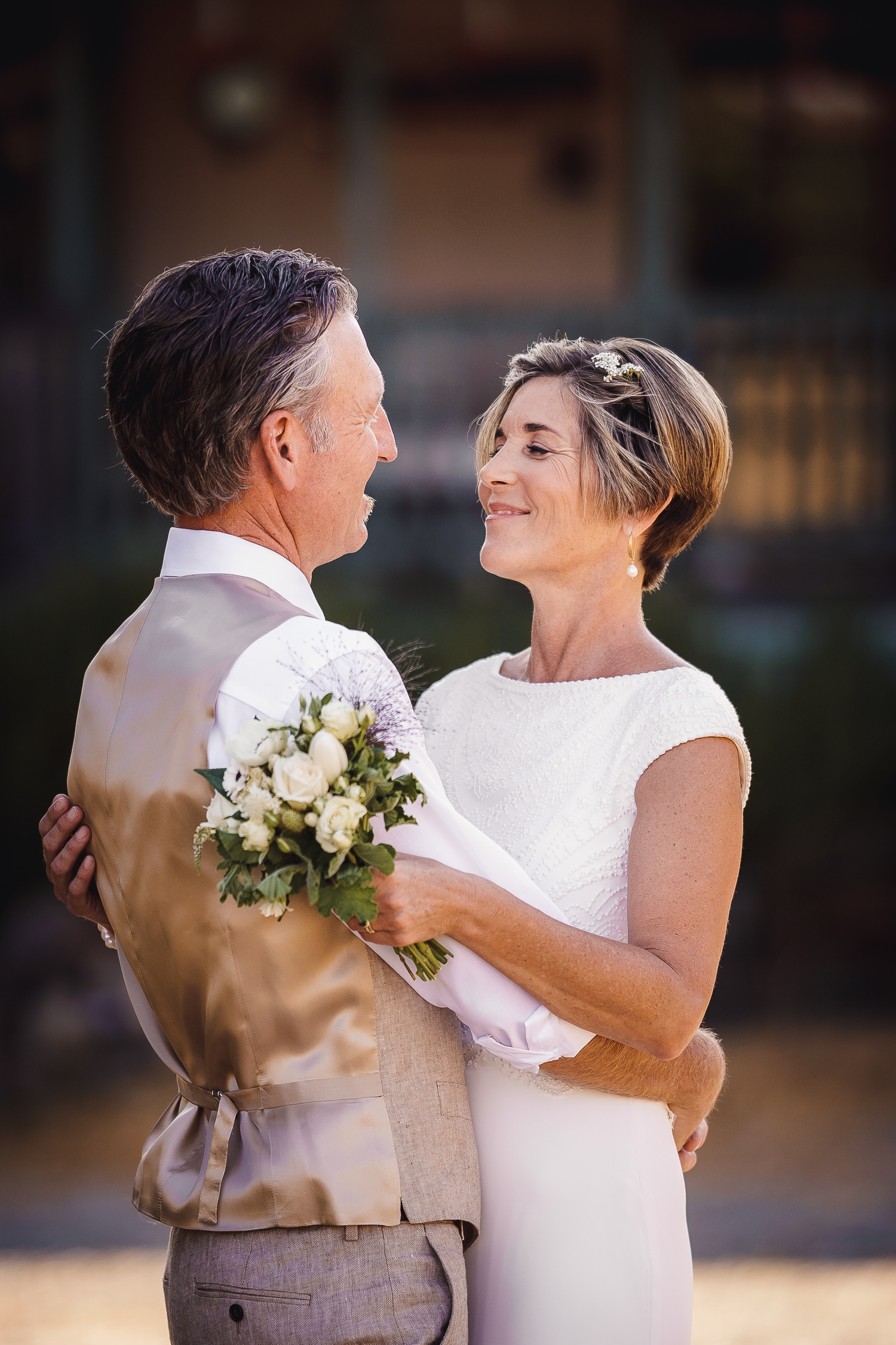 A couple dances together in formal wedding attire against a rustic backdrop at Cow-Track Ranch in Marin County.