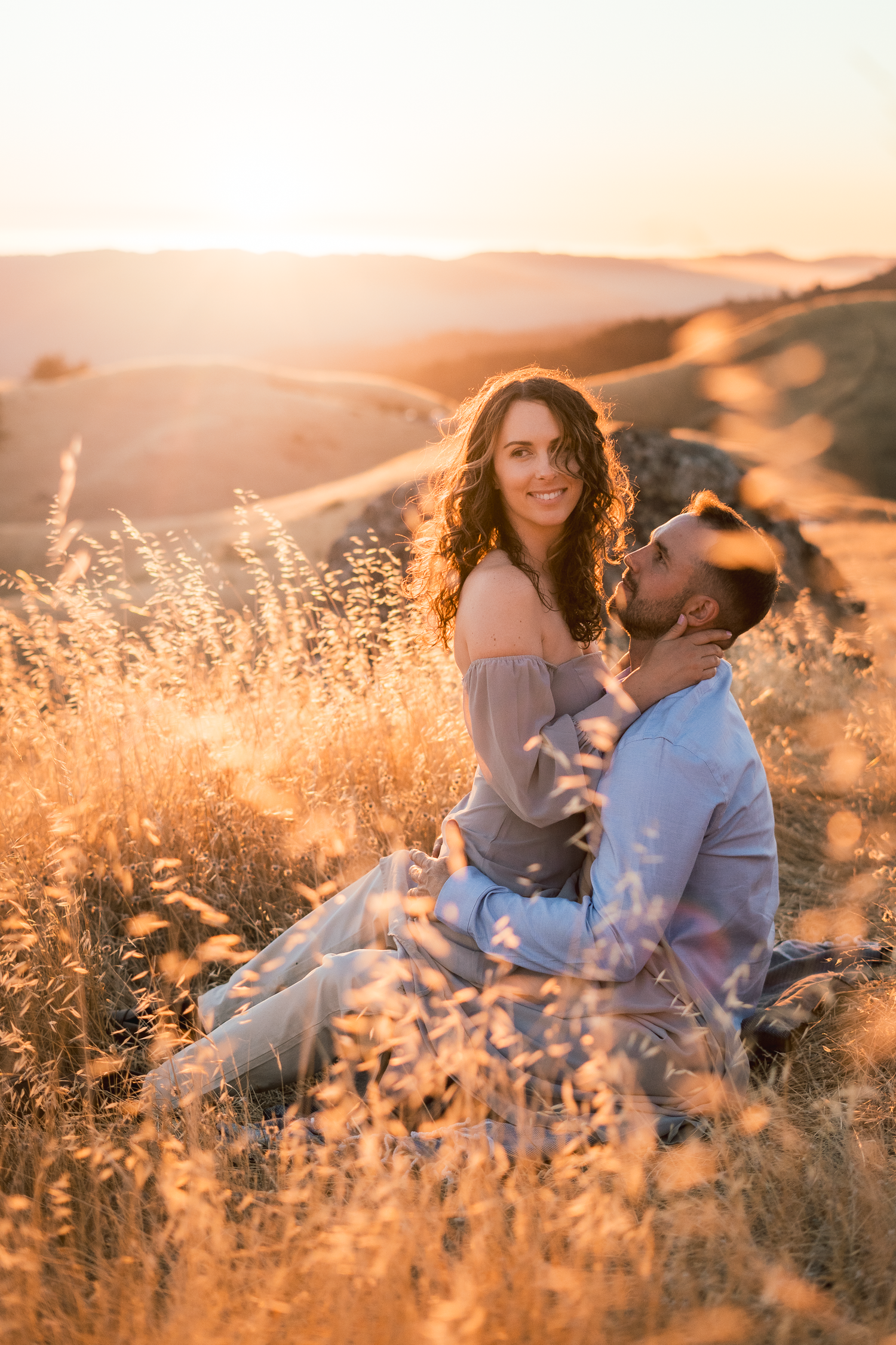 A romantic sunset photoshoot in tall golden grass creates dreamy, warm-toned portraits.