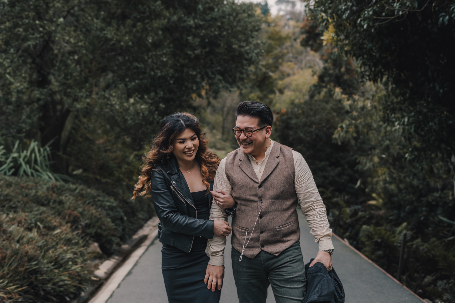 A couple shares romantic moments together during an outdoor engagement photo session in a lush garden setting.