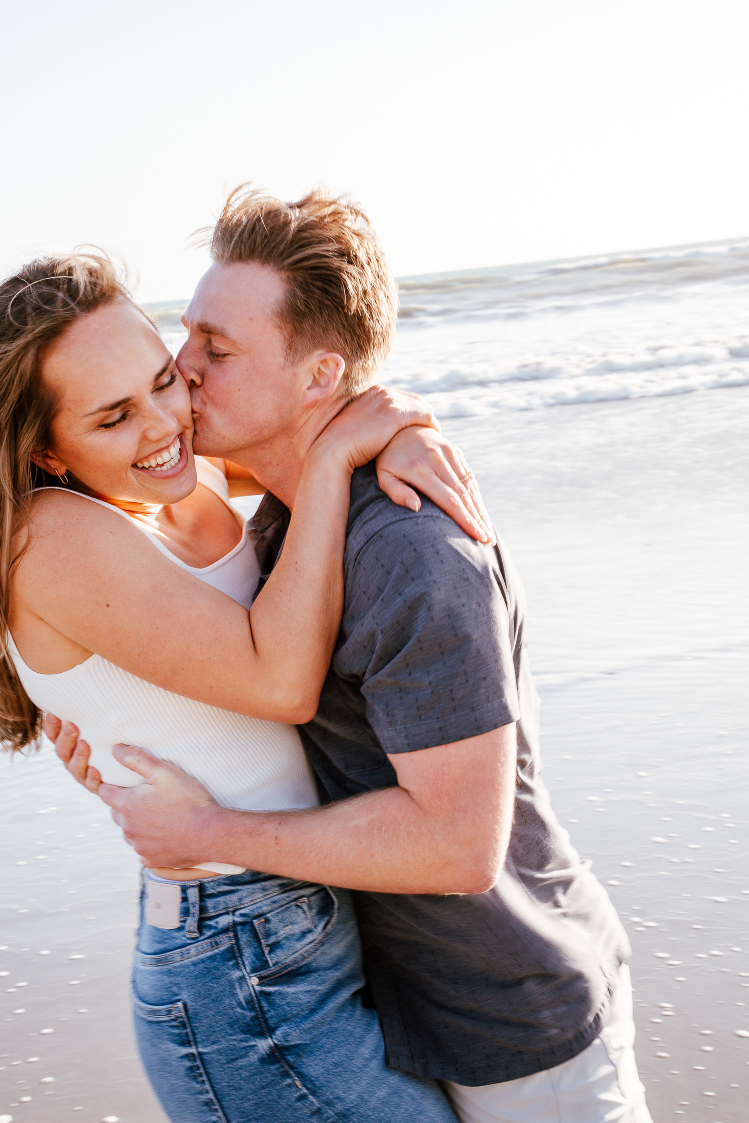 Candid beach photos of couple embracing and laughing in casual attire at Stinson Beach in Marin County.
