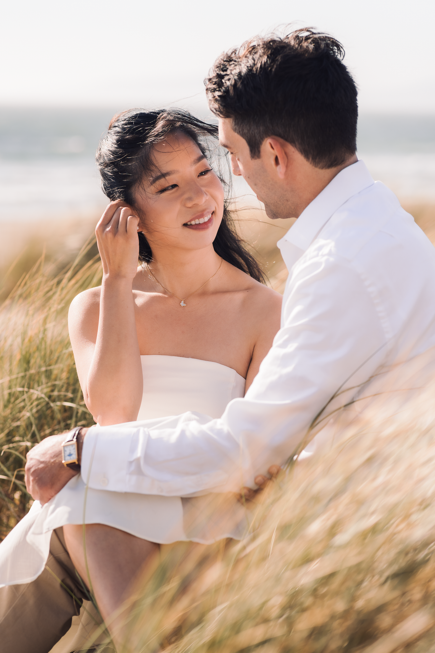 Intimate moment captured between couple in flowing beach grass at Ocean Beach in San Francisco.
