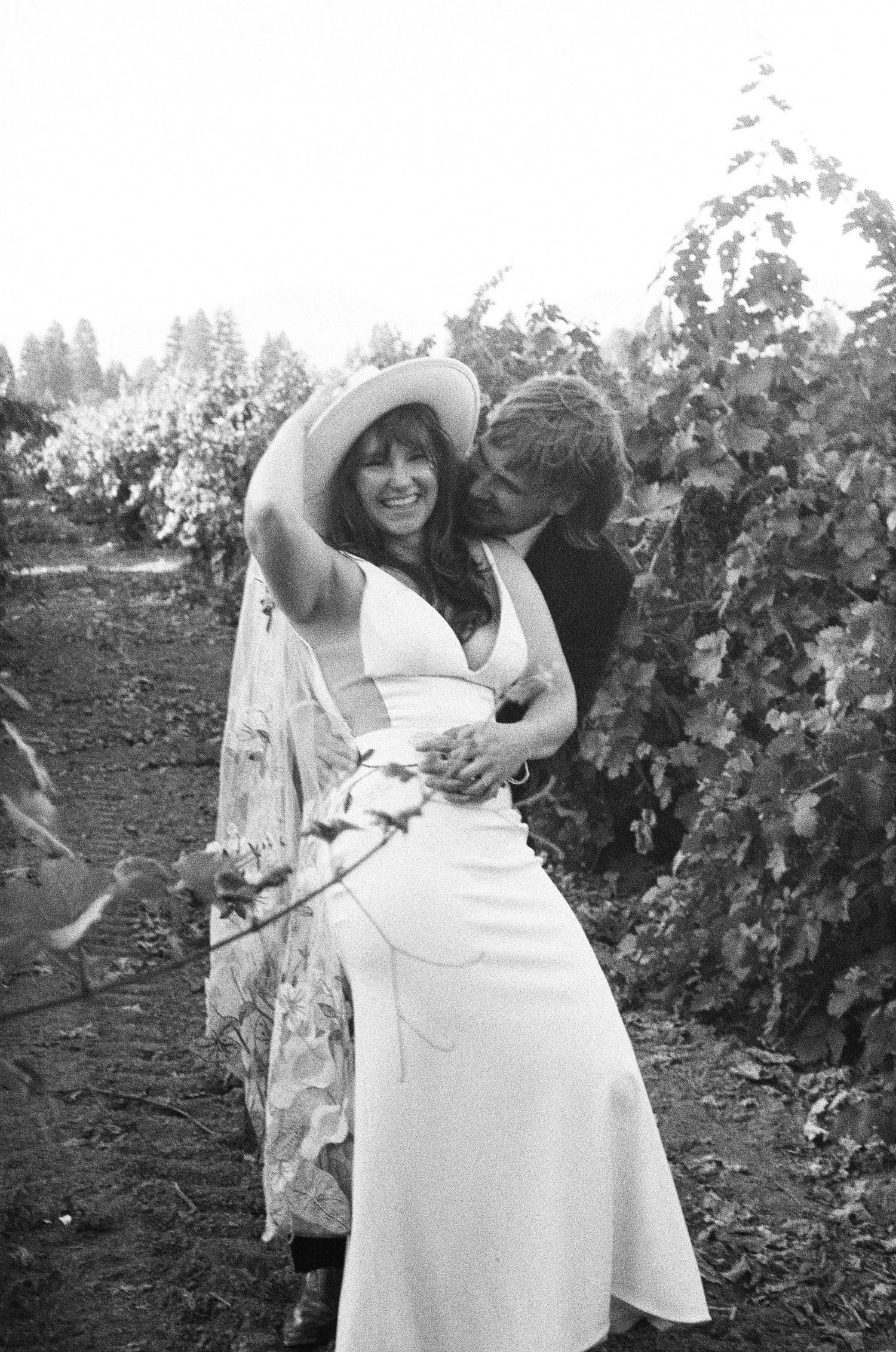 Wedding couple posing in a vineyard with white dress and natural scenery. Photographed on film in the North Bay