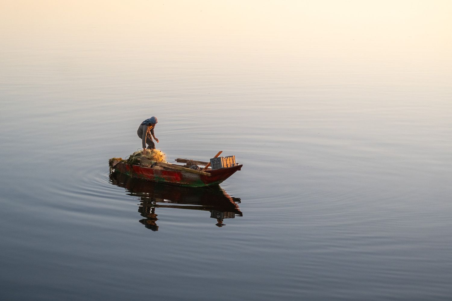 Small boats on calm reflective water during golden hour.