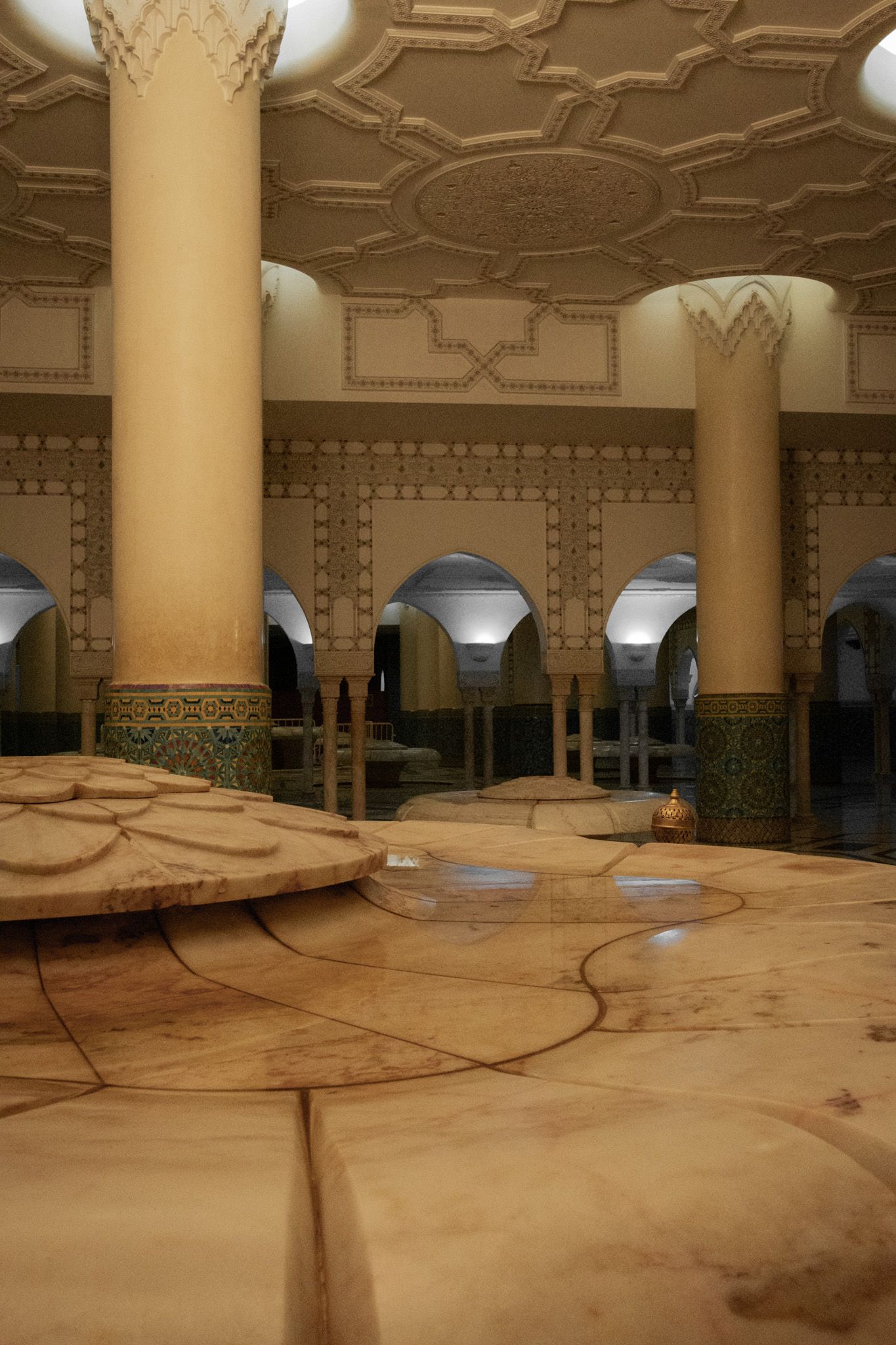 Ornate interior with decorated columns and geometric ceiling patterns in warm golden tones.