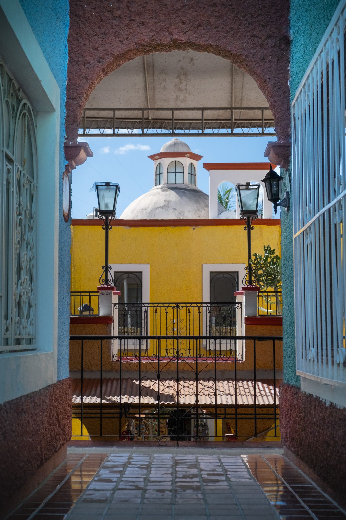 Colorful colonial architecture with yellow walls and blue trim viewed through an archway.