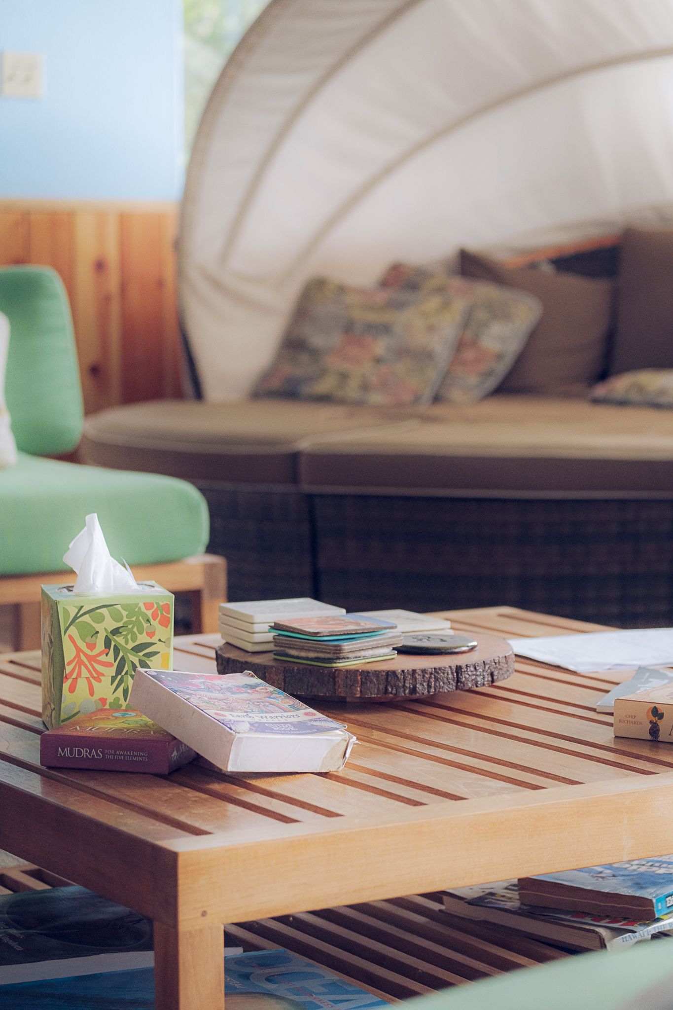 Books and decorative items arranged on a wooden slatted coffee table with green chair in background.
