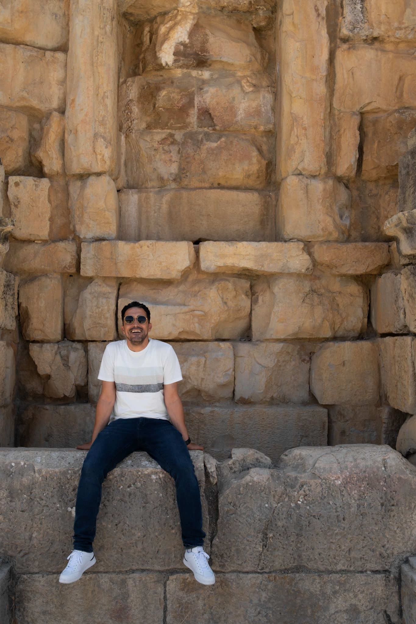 Person sitting on ancient stone steps against weathered temple wall.