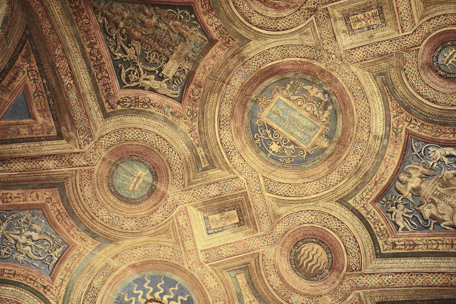 Ornate baroque ceiling with gilded decorative circles and religious artwork.
