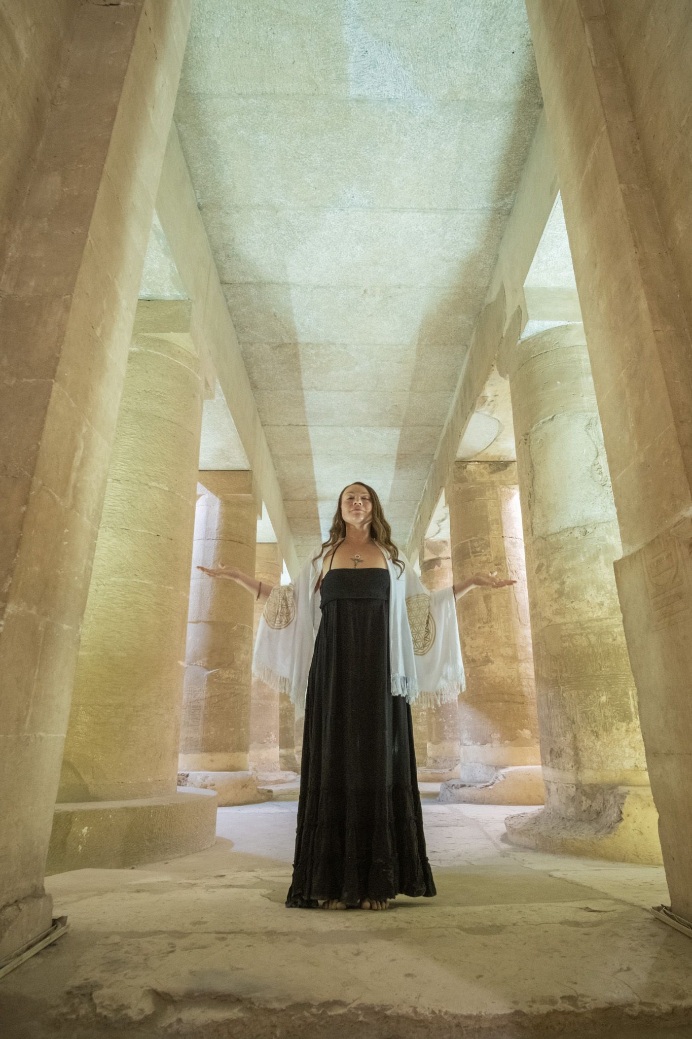 Dramatic architectural photo of pillared hallway with stone columns in natural light.