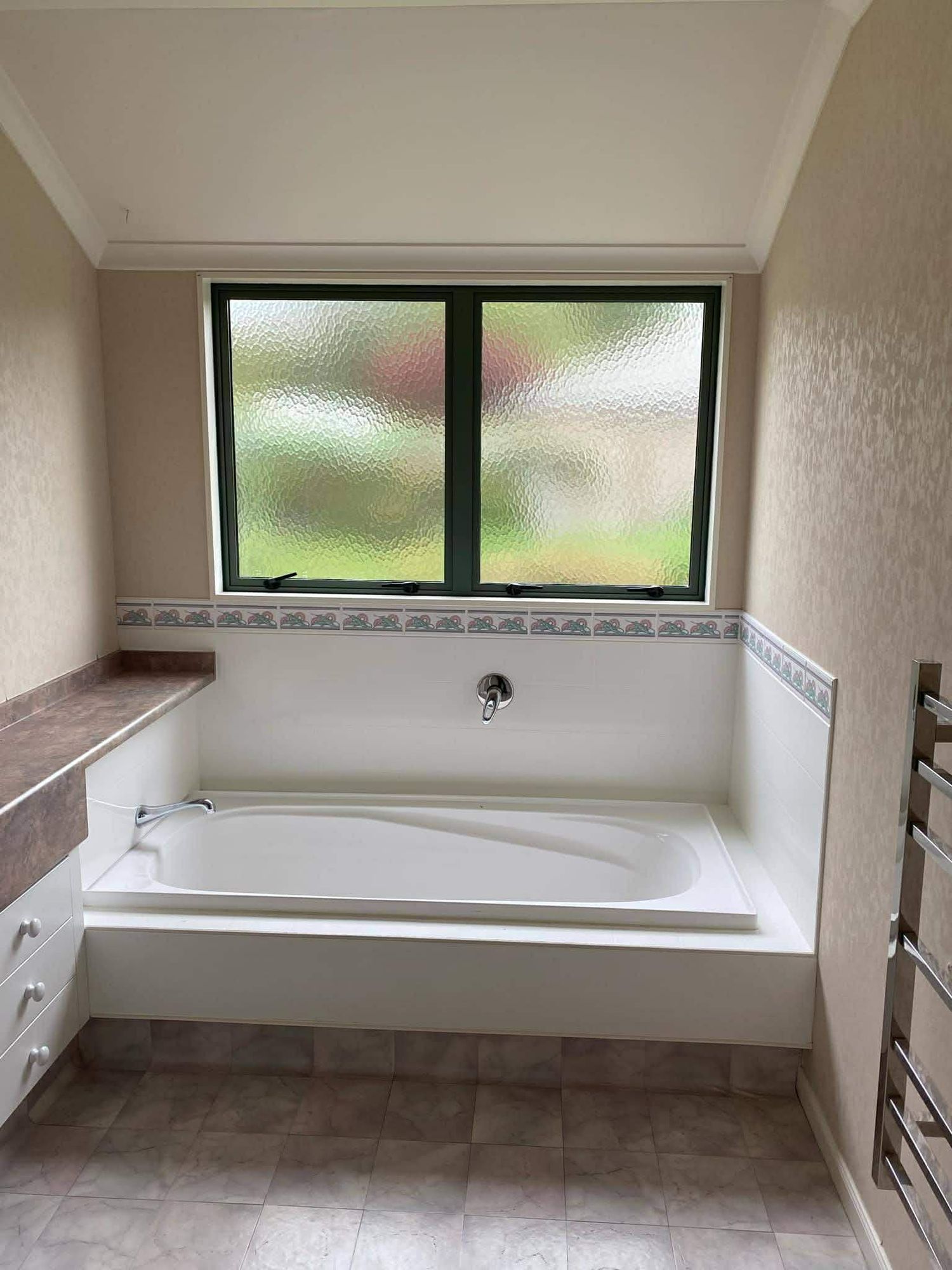 Bathroom renovation progress showing white walls, windows, and built-in storage in various stages of completion.