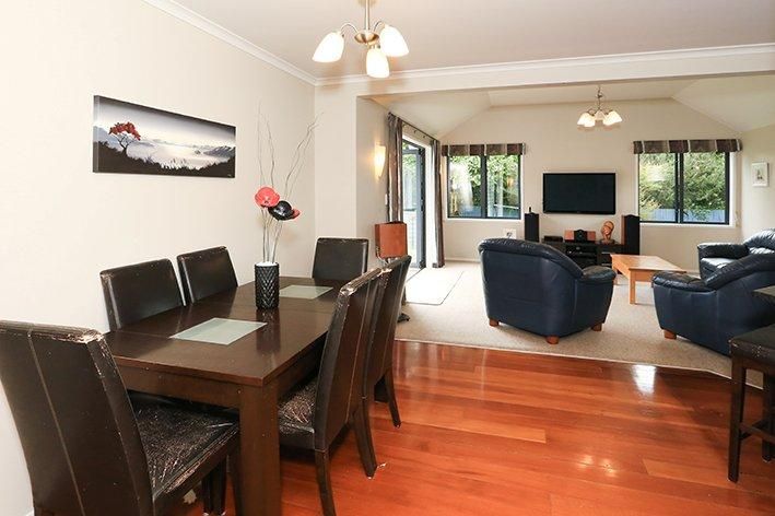 Modern open concept living and dining area with hardwood floors and navy blue furniture.