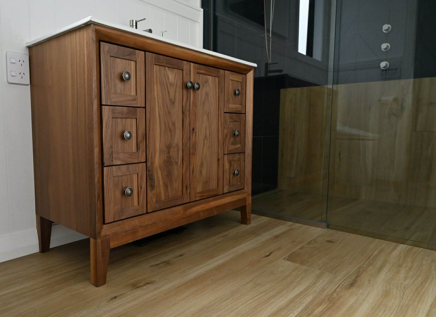 Wooden bathroom vanity with multiple drawers and sleek modern hardware.