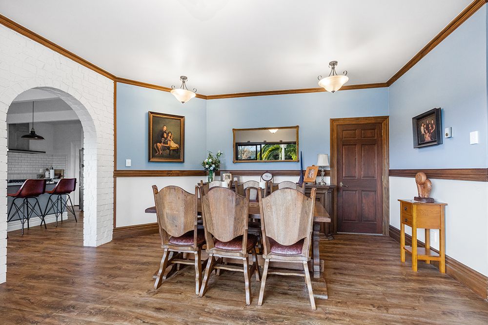 Traditional dining room with wooden trim, blue walls, and classic furniture arrangement.