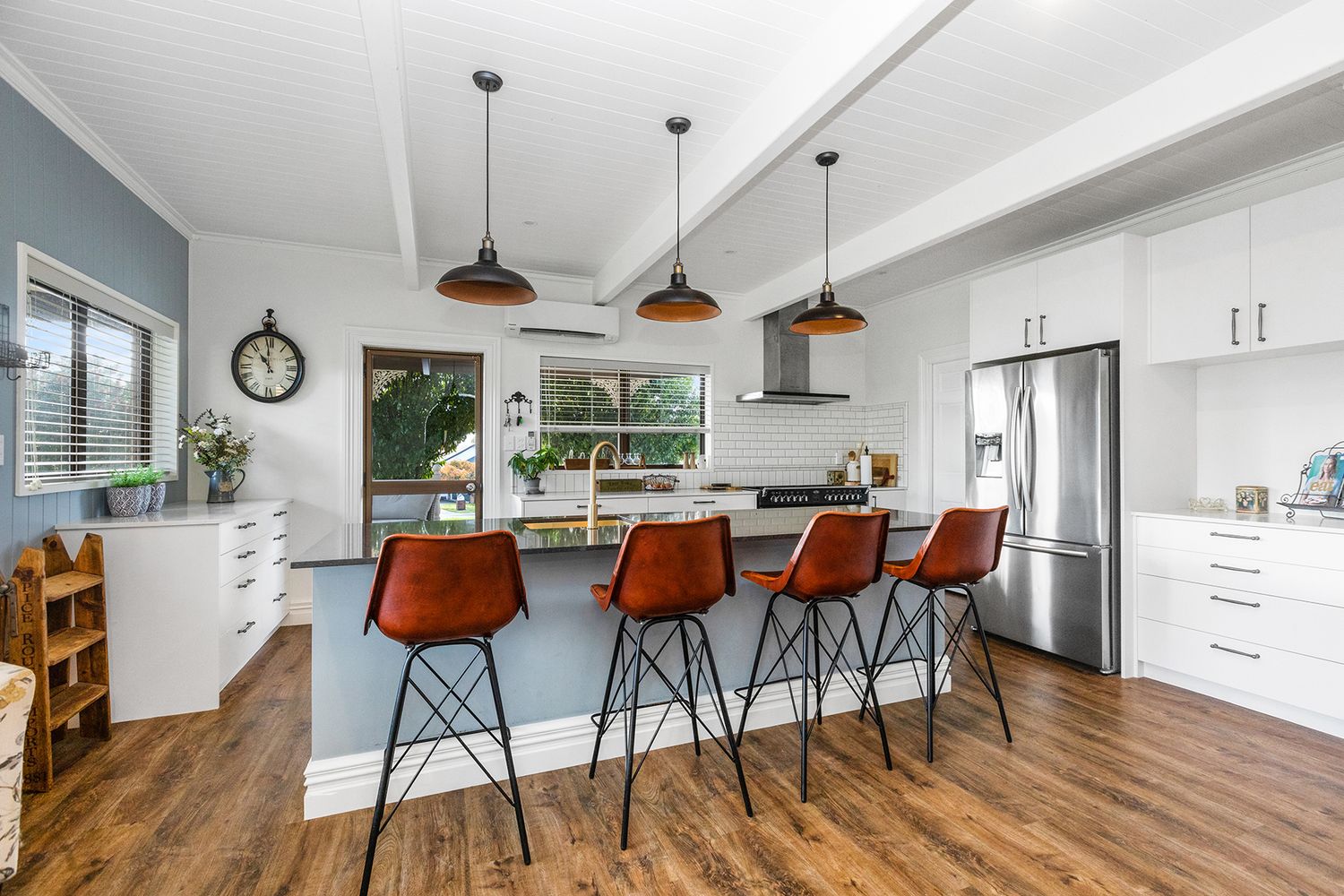 Bright contemporary kitchen with white cabinets and multiple bar stools along an extended counter space.