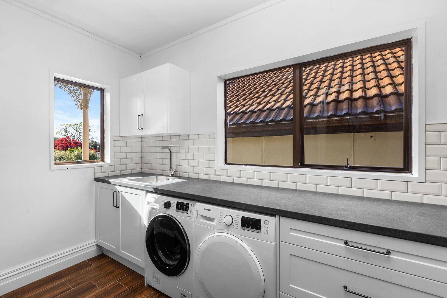 Bright laundry room with white subway tile backsplash, counter space, and window letting in natural light.