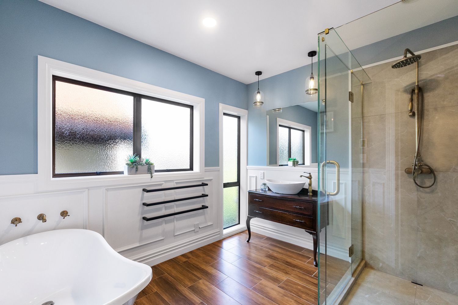 Contemporary bathroom featuring glass shower enclosure, blue accent wall, and modern fixtures.
