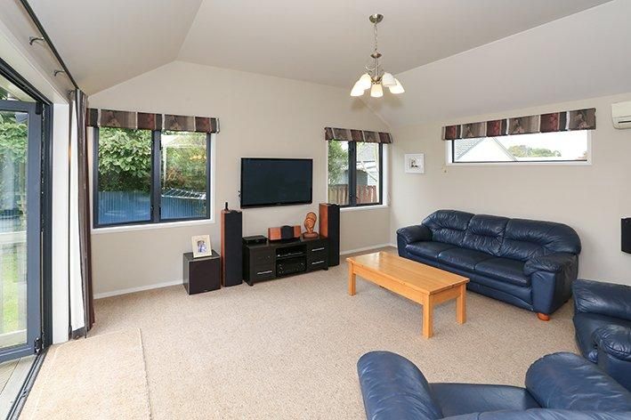Bright living room with blue couches, beige carpet, and sliding glass doors leading outside.