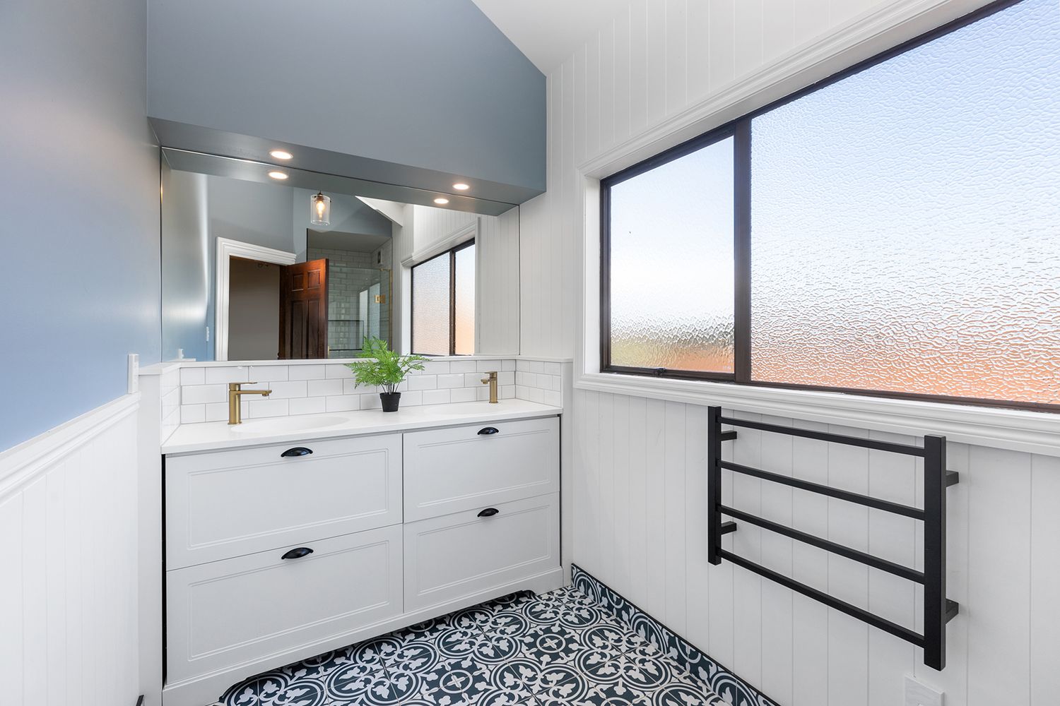 White bathroom interior with black hardware, geometric floor tiles, and built-in storage.