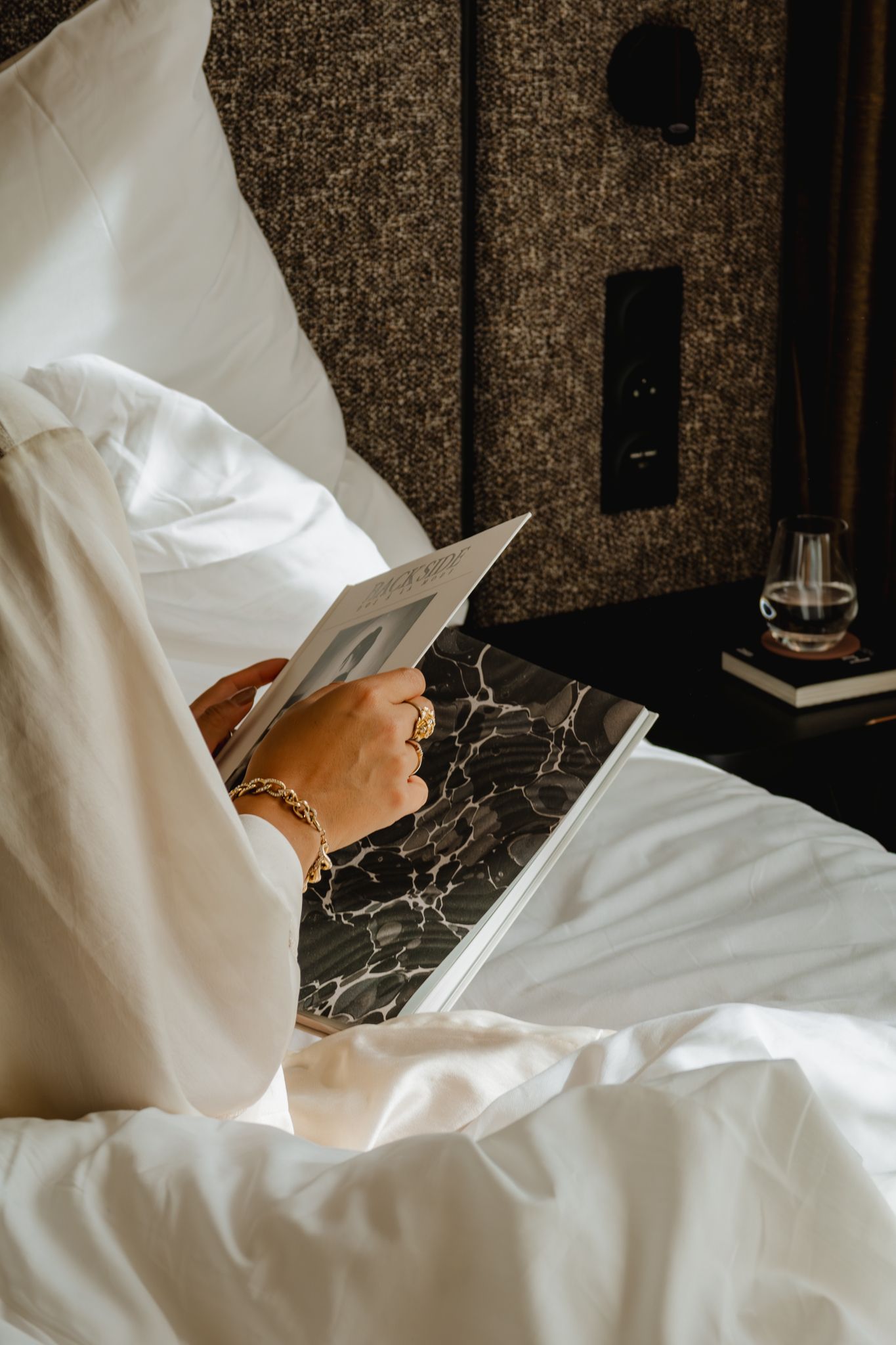 A cozy scene showing someone reading in bed with crisp white linens and a marble laptop desk.