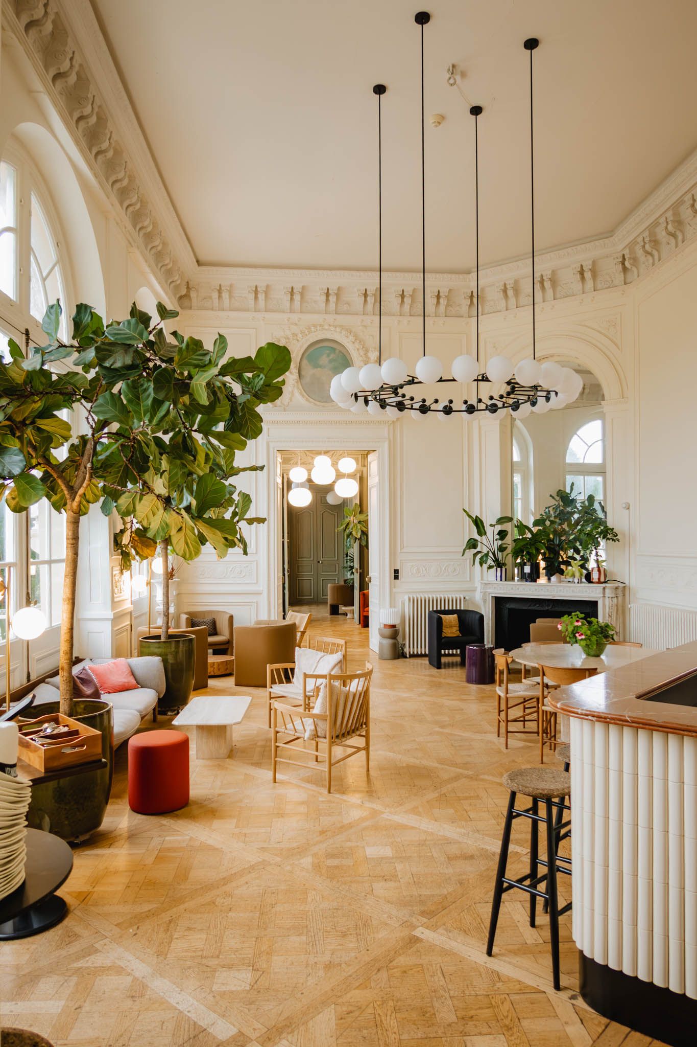 Modern coworking space interior with elegant white crown molding, herringbone floors and hanging pendant lights.
